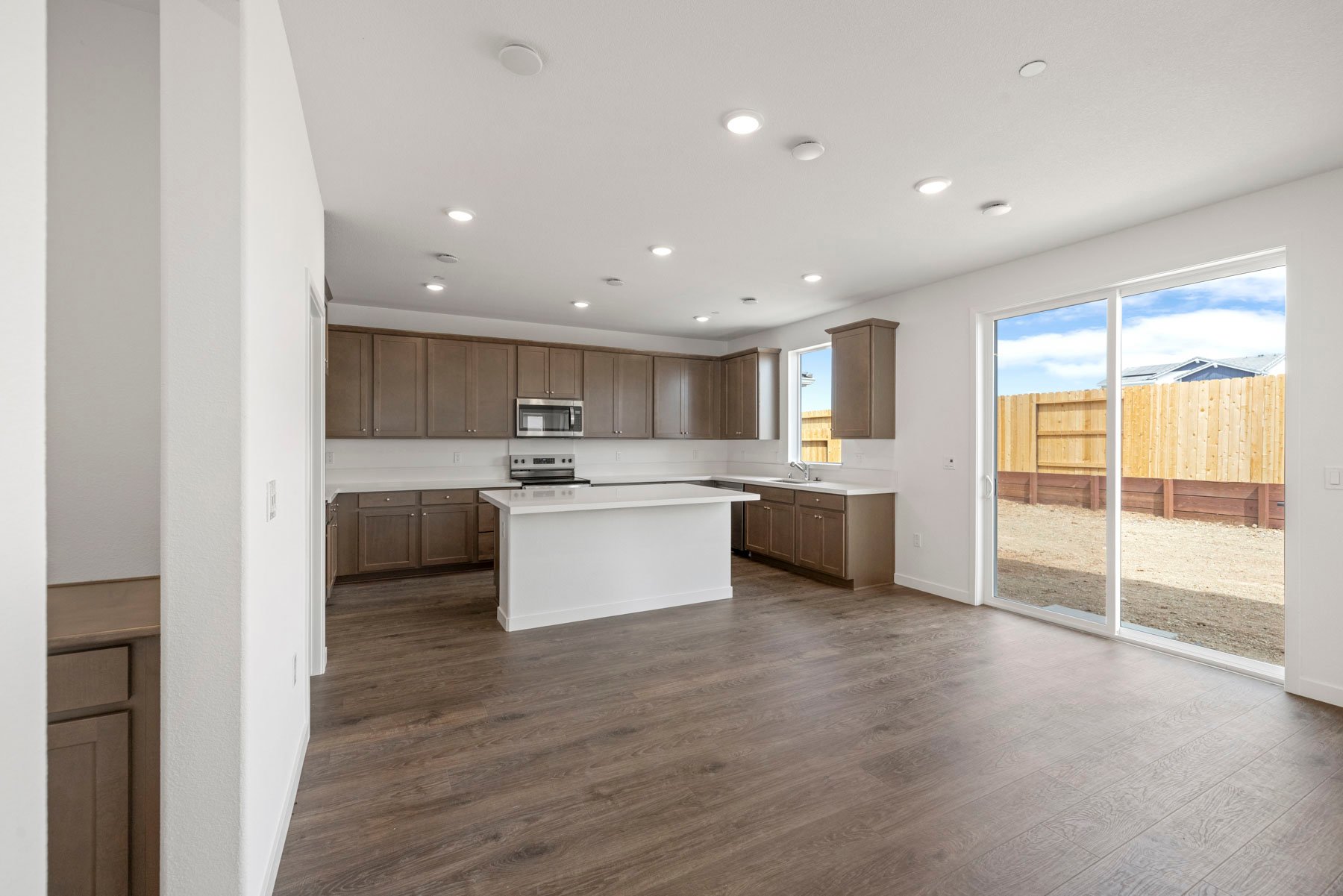 dining room with wood floors, sliding glass door to the backyard, and view of adjacent kitchen