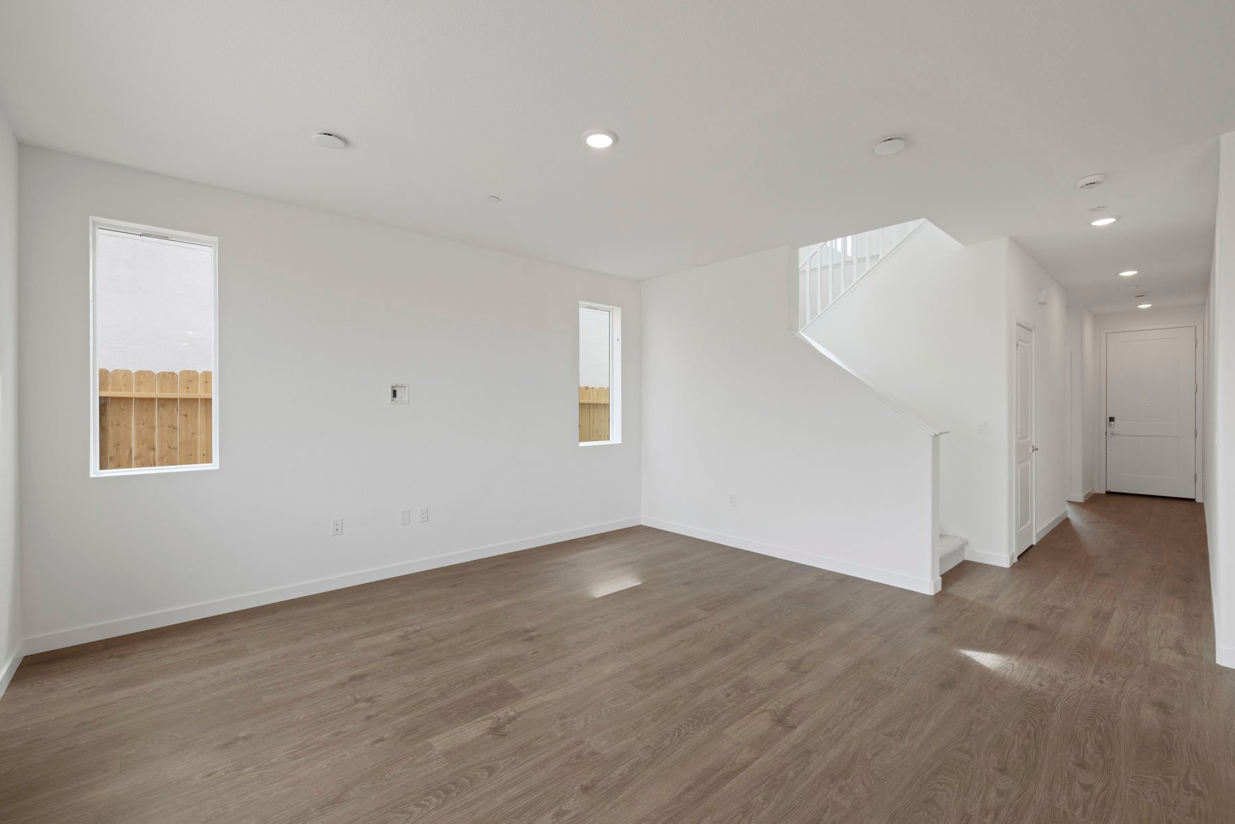 great room with wood floors, white walls, and two windows