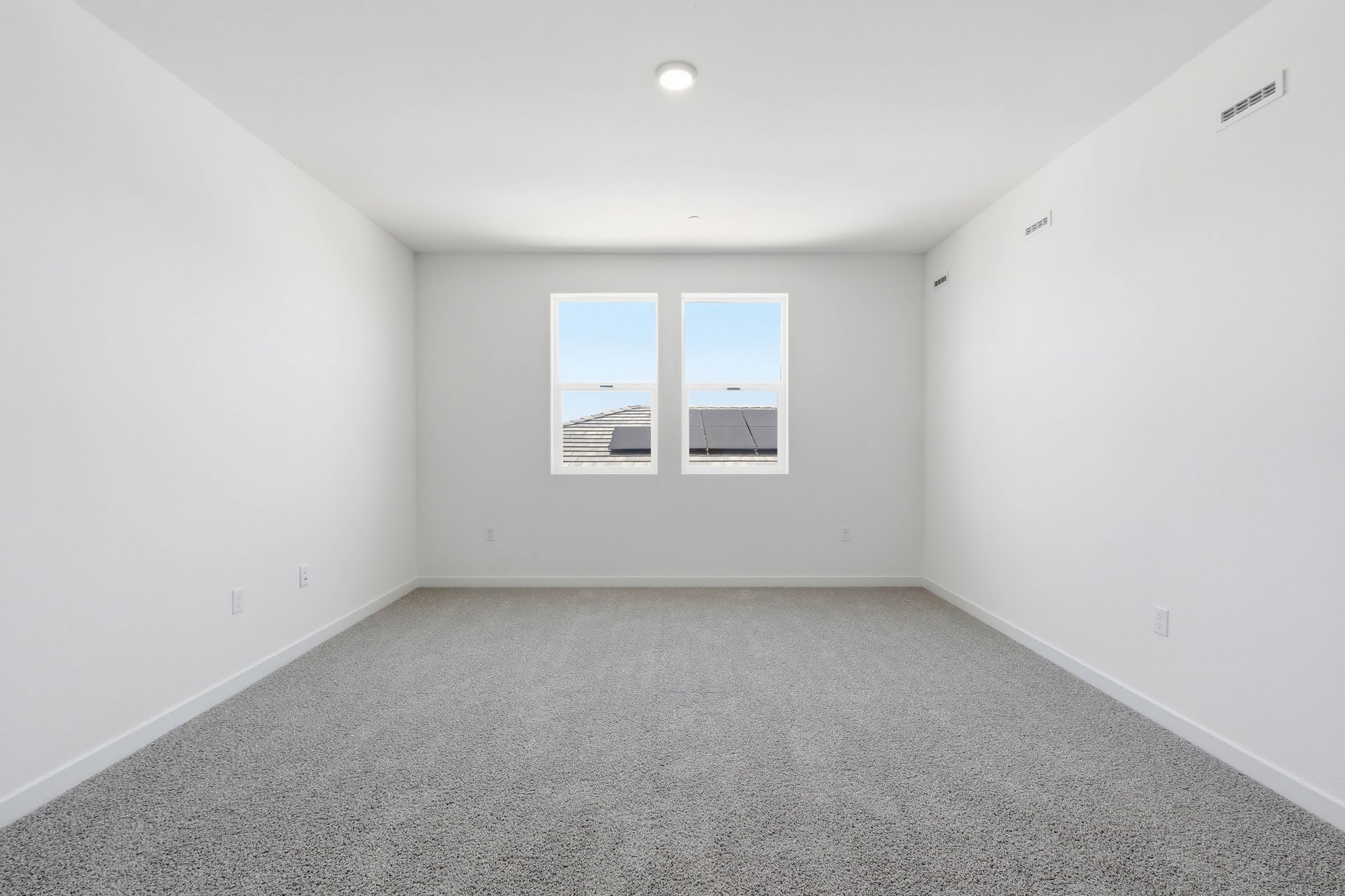 loft with tan carpet, white walls, and two windows