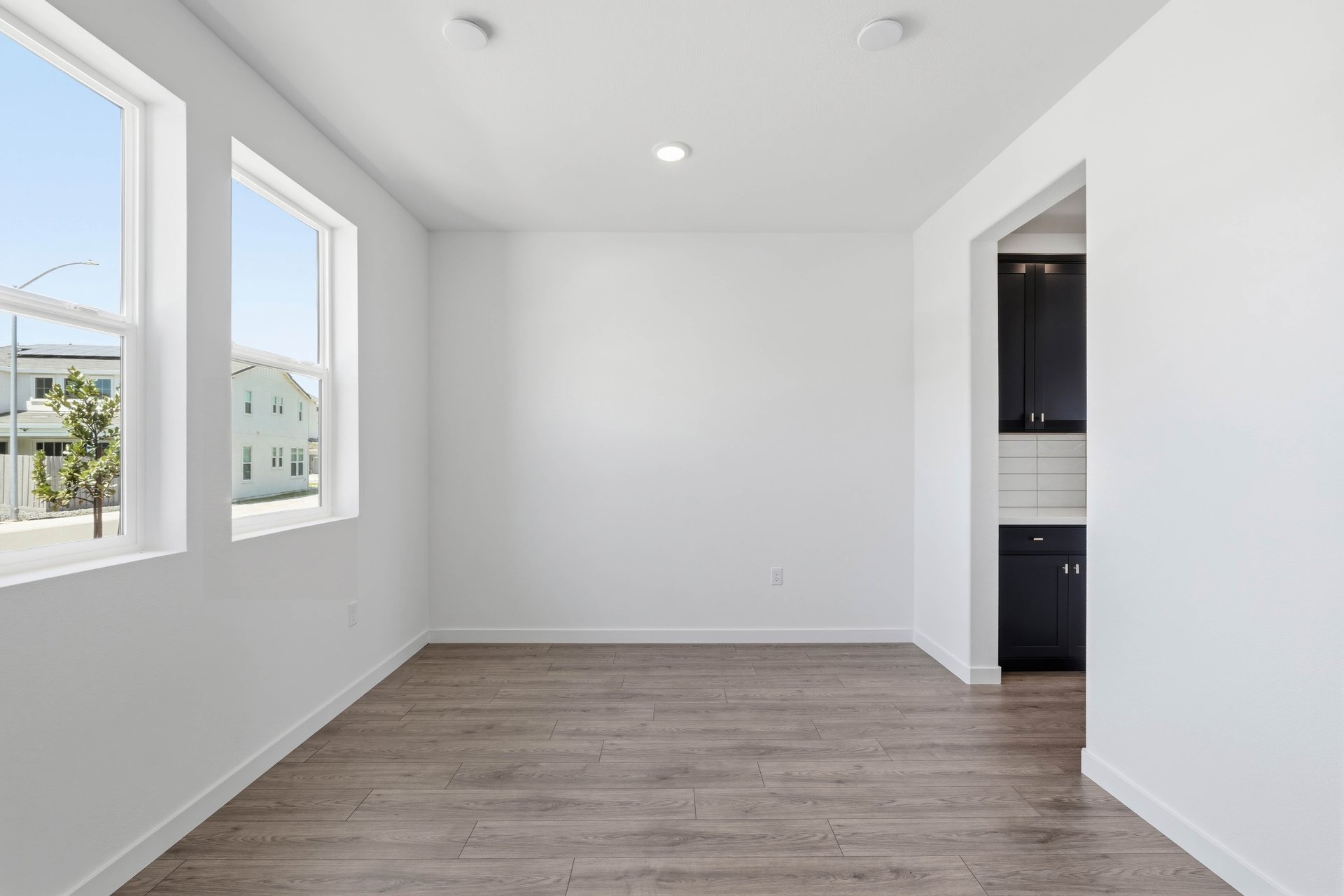 dining room with wood floors, white walls, recessed ceiling lights, and two windows looking out to the front yard