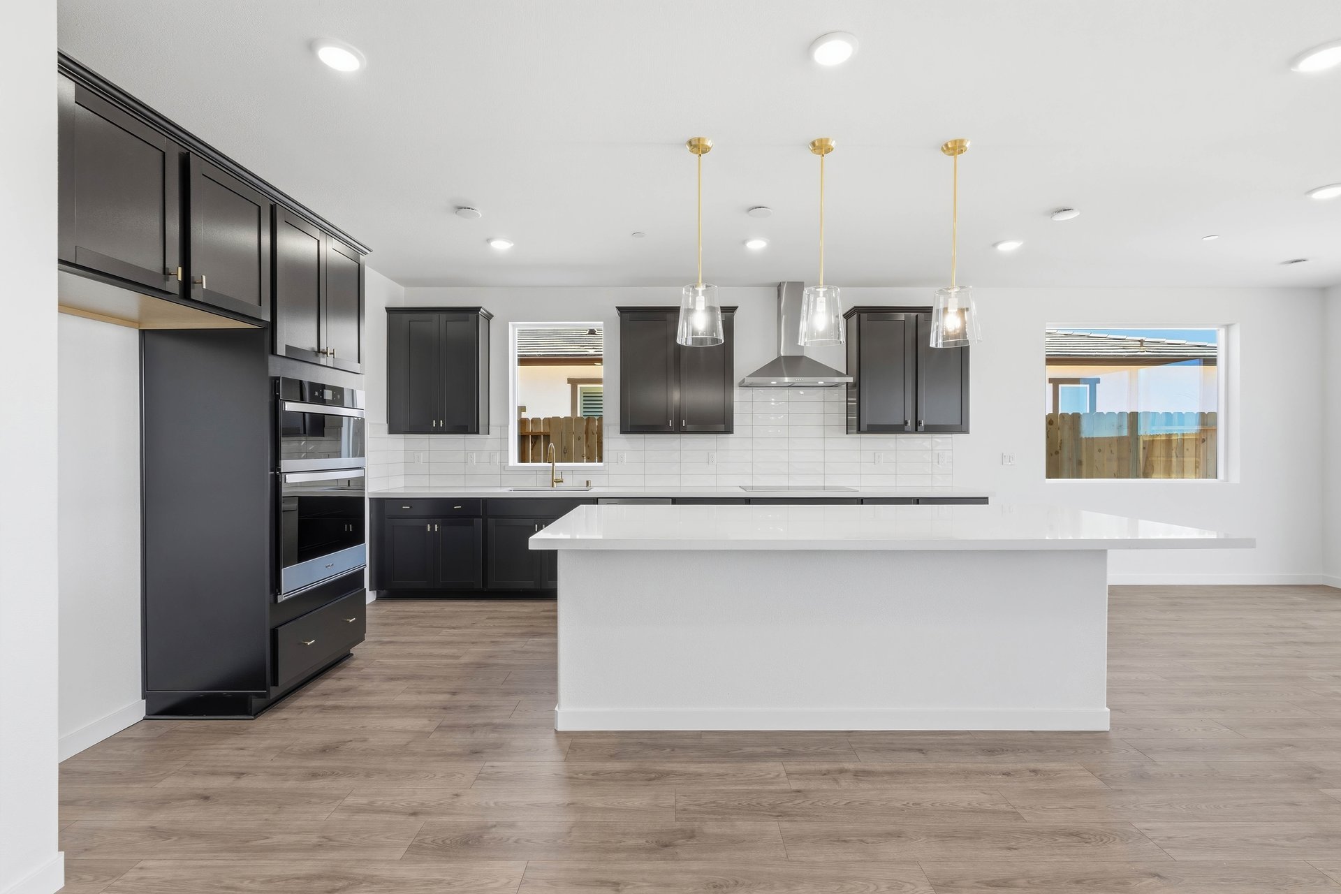 kitchen with wood floors, espresso cabinets, white quartz counters, island, and window above sink