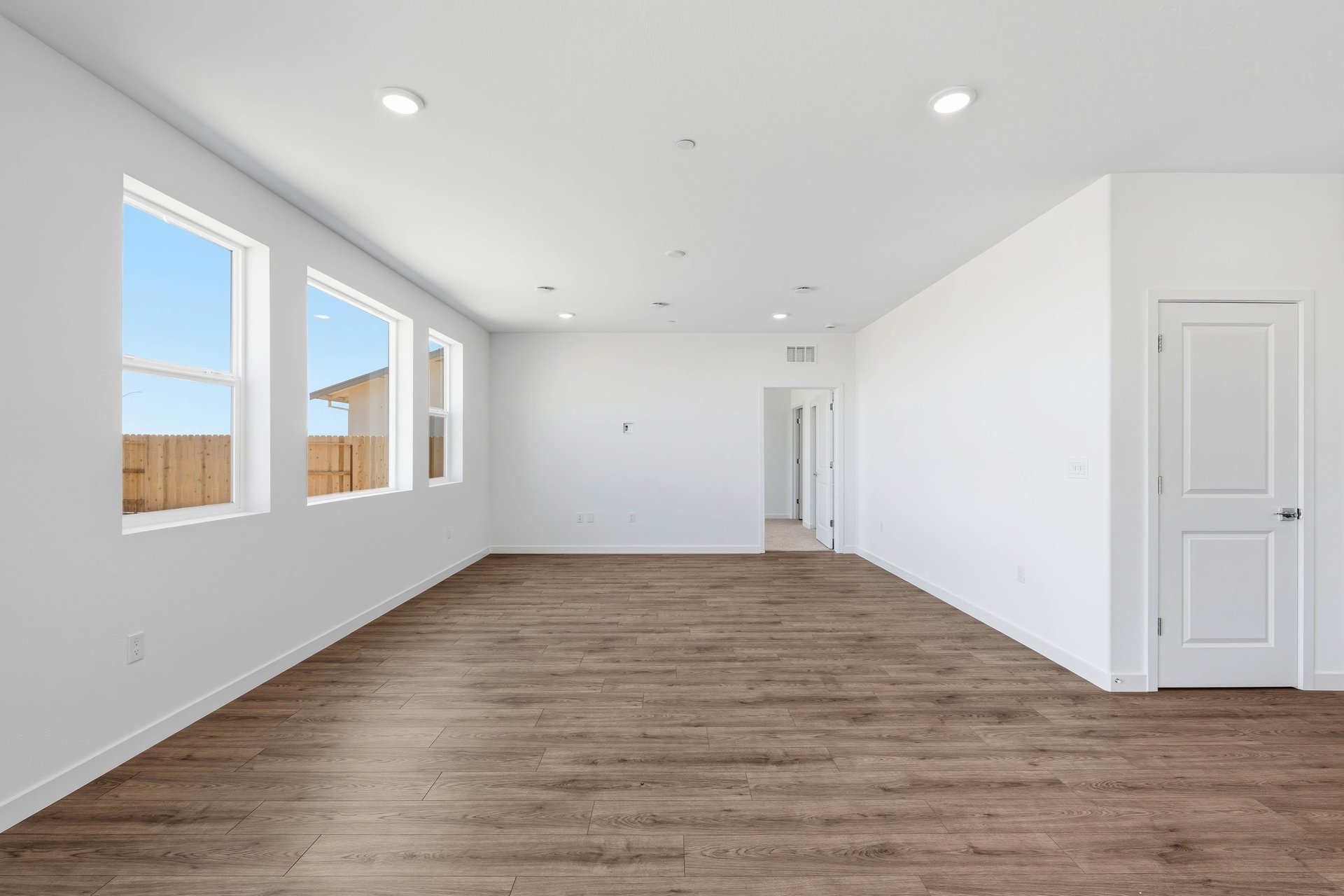 great room with wood floors, white walls, multiple windows, and recessed ceiling lights