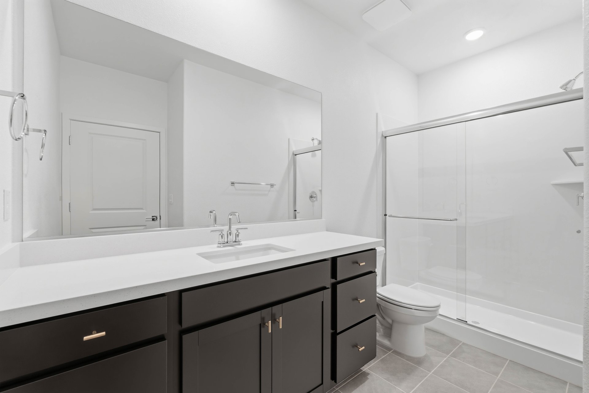 bathroom with espresso cabinets, white quartz counters, and walk-in shower