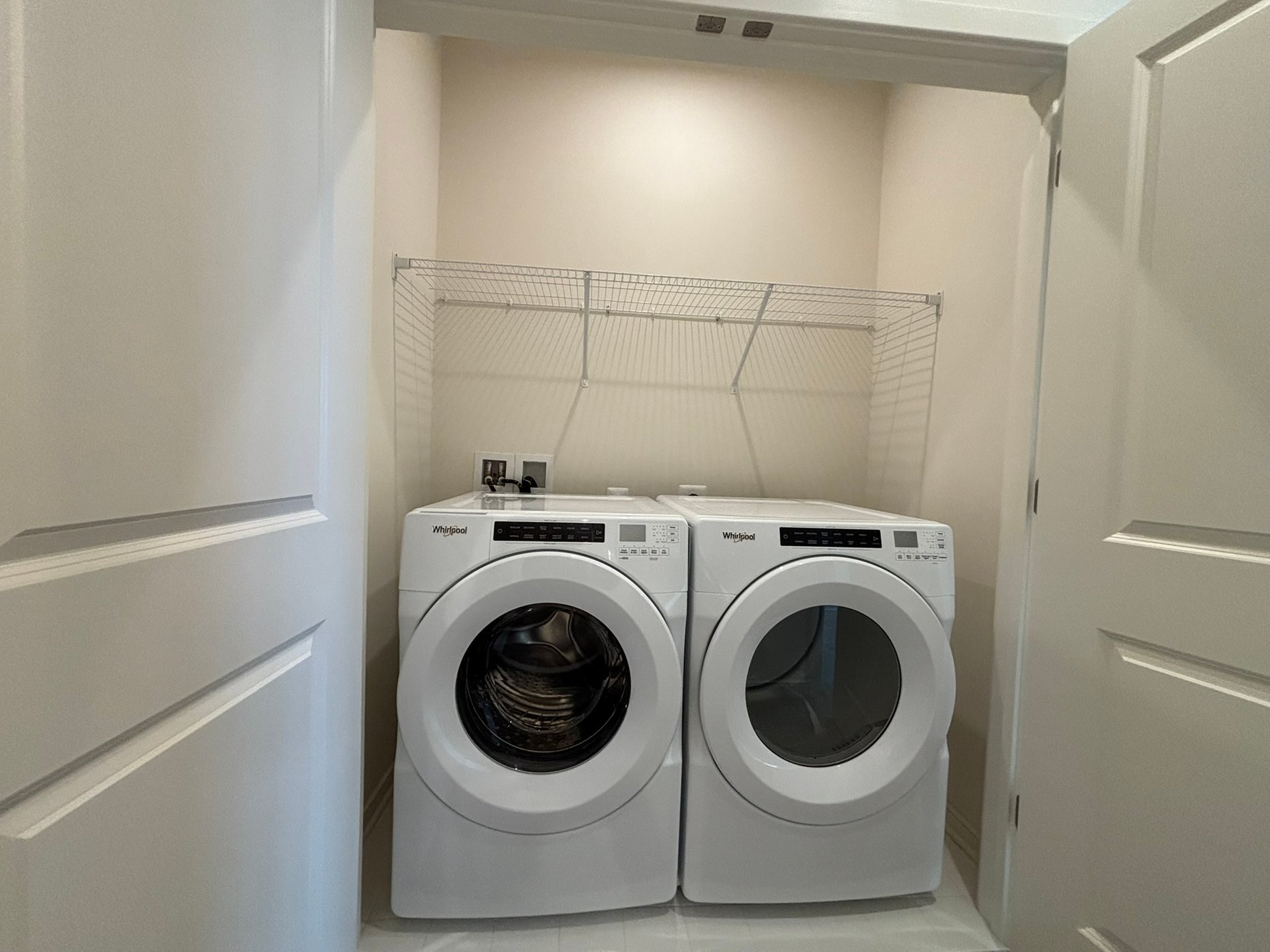laundry with a washer, dryer and a wire shelf