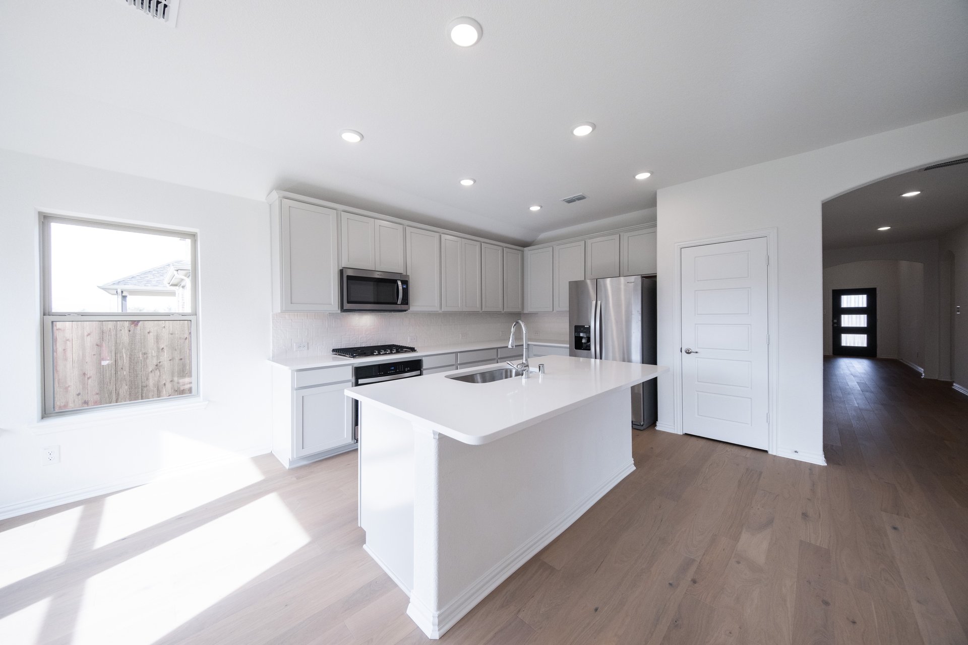 open kitchen with wood floors and white cabinets