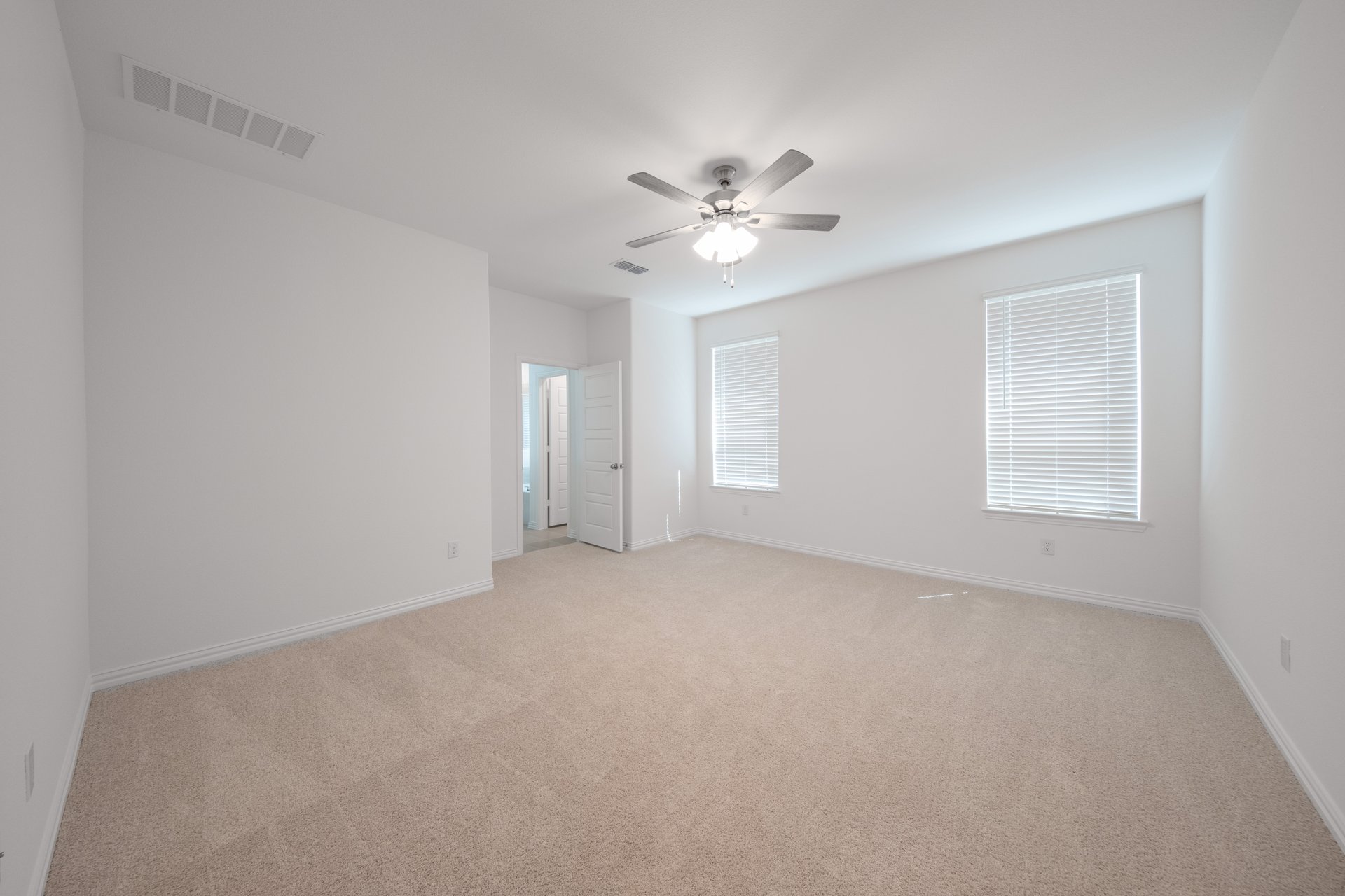 large primary bedroom with carpet and windows