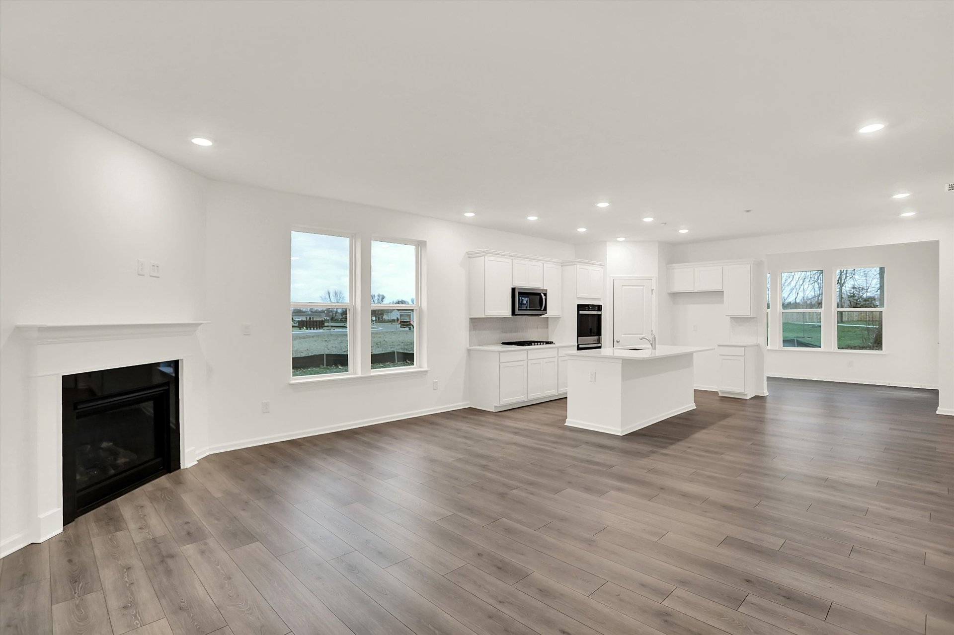 great room with fireplace and wood plank flooring that is open to the kitchen