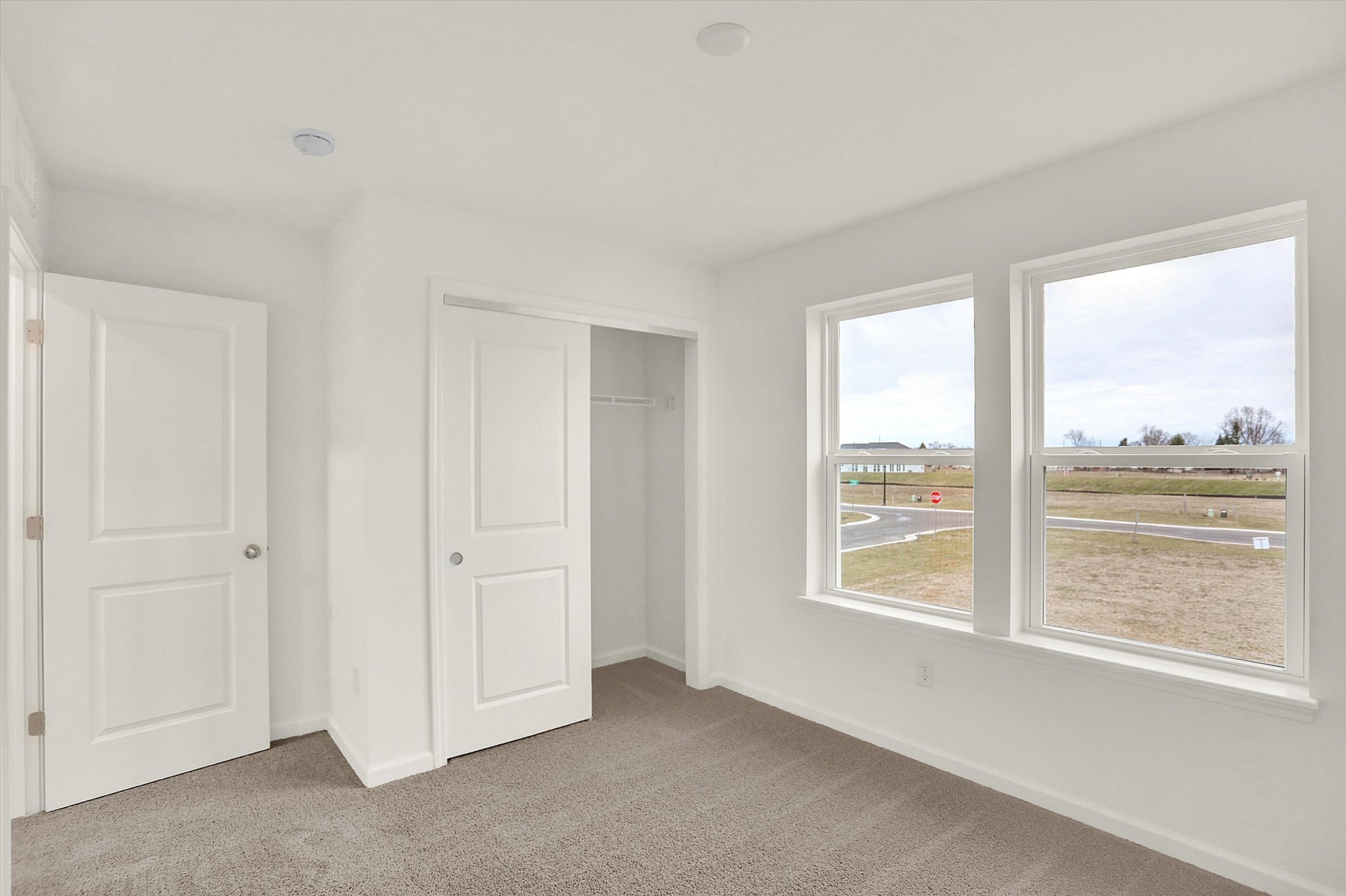 secondary bedroom with tan carpet closet and window