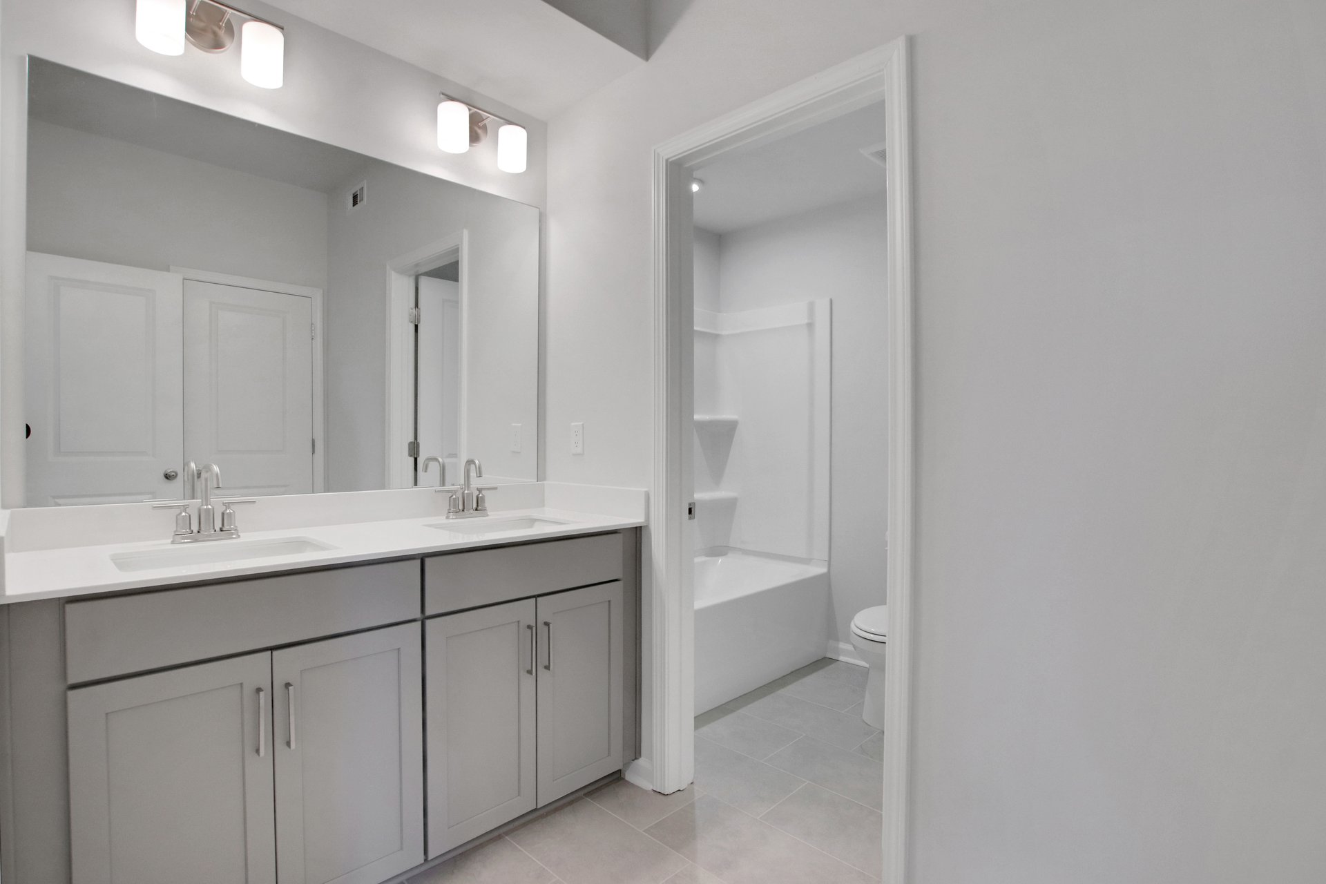 secondary bathroom with gray cabinets and tile flooring