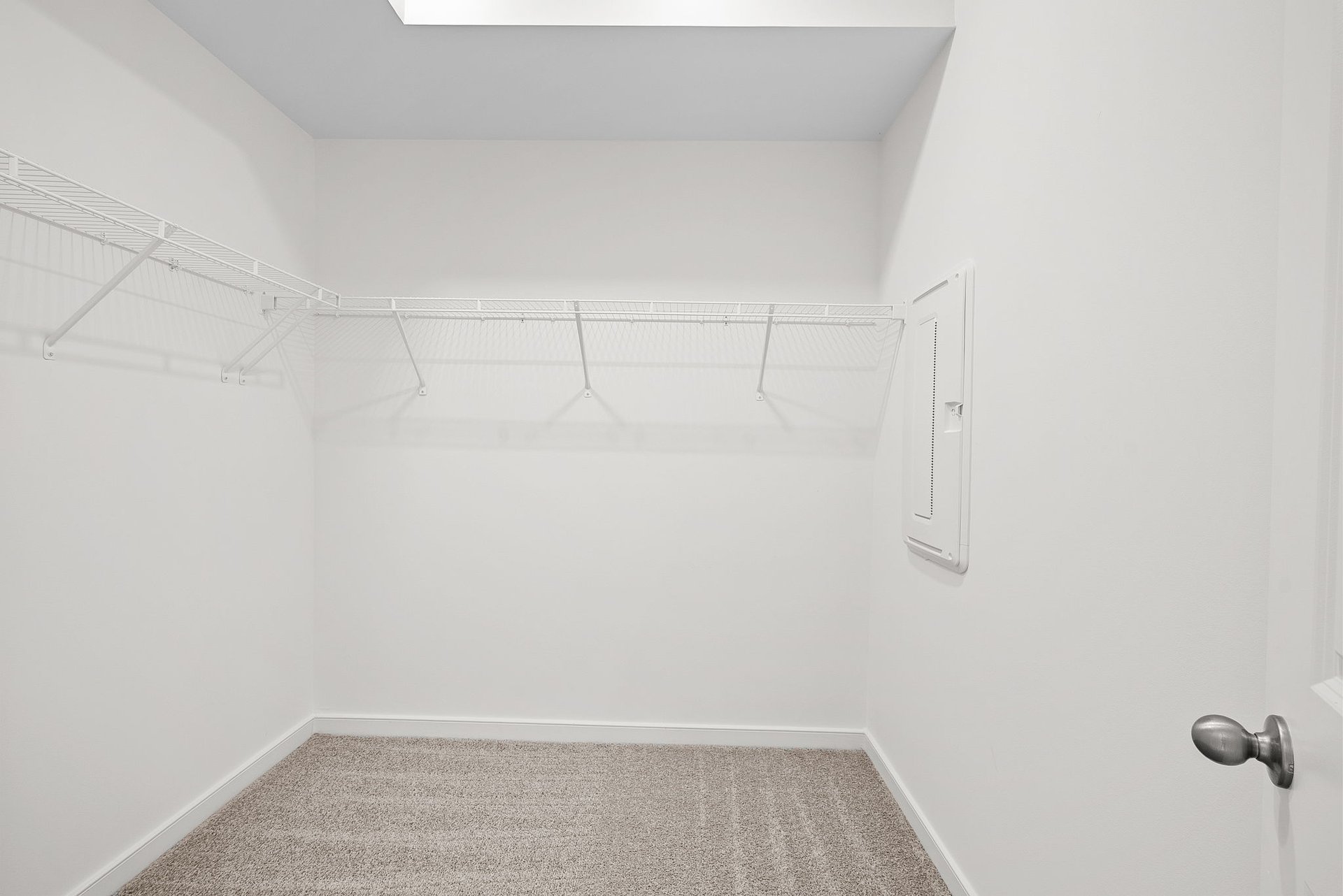 walk-in closet with white rack on top