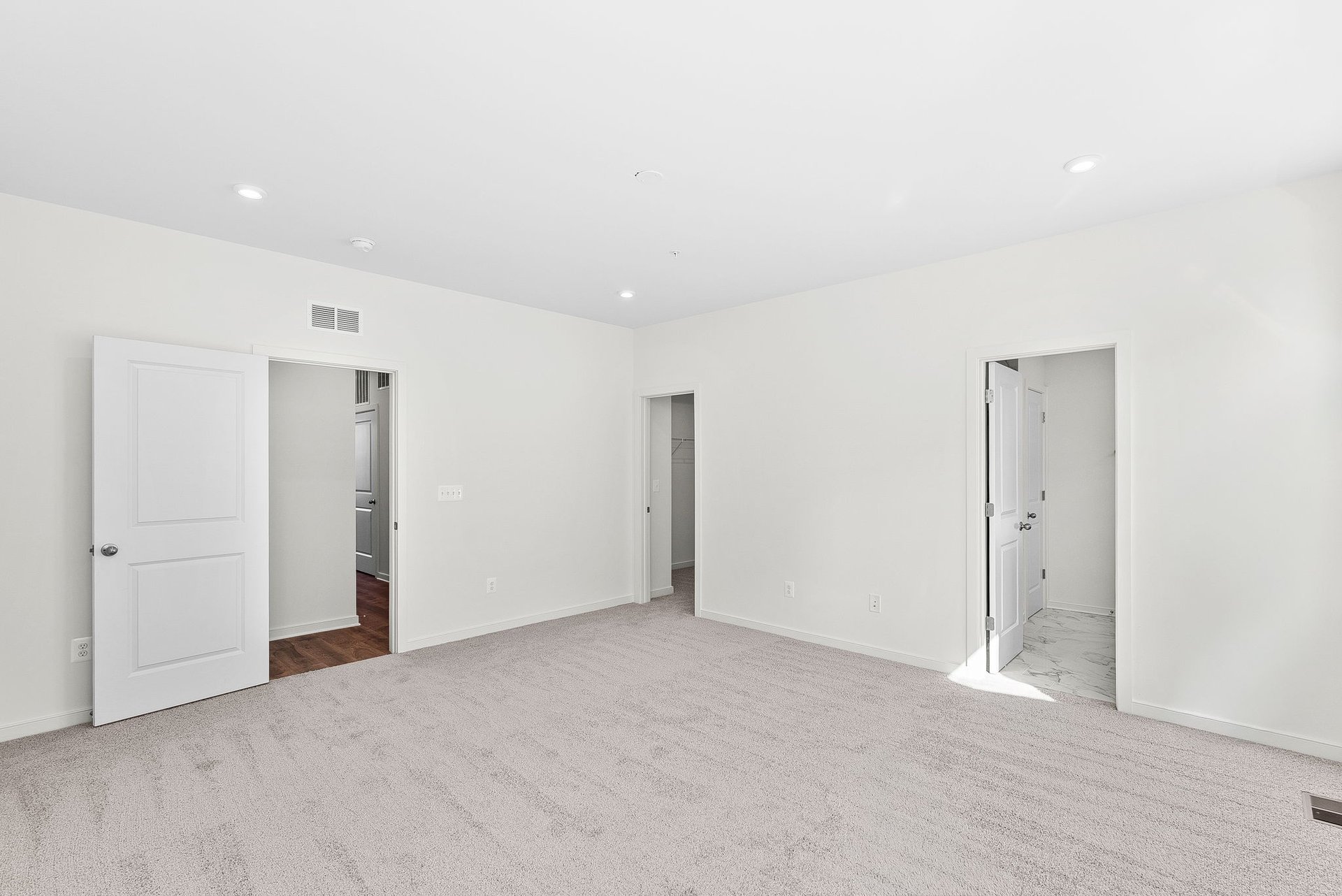 Primary bedroom with three doors to walk-in closet, hallway, and primary bathroom