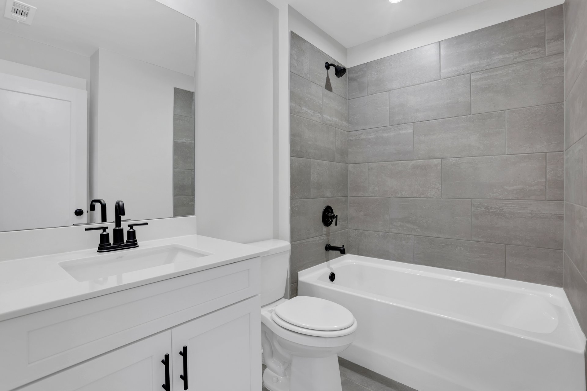 bathroom with white cabinets and tile shower