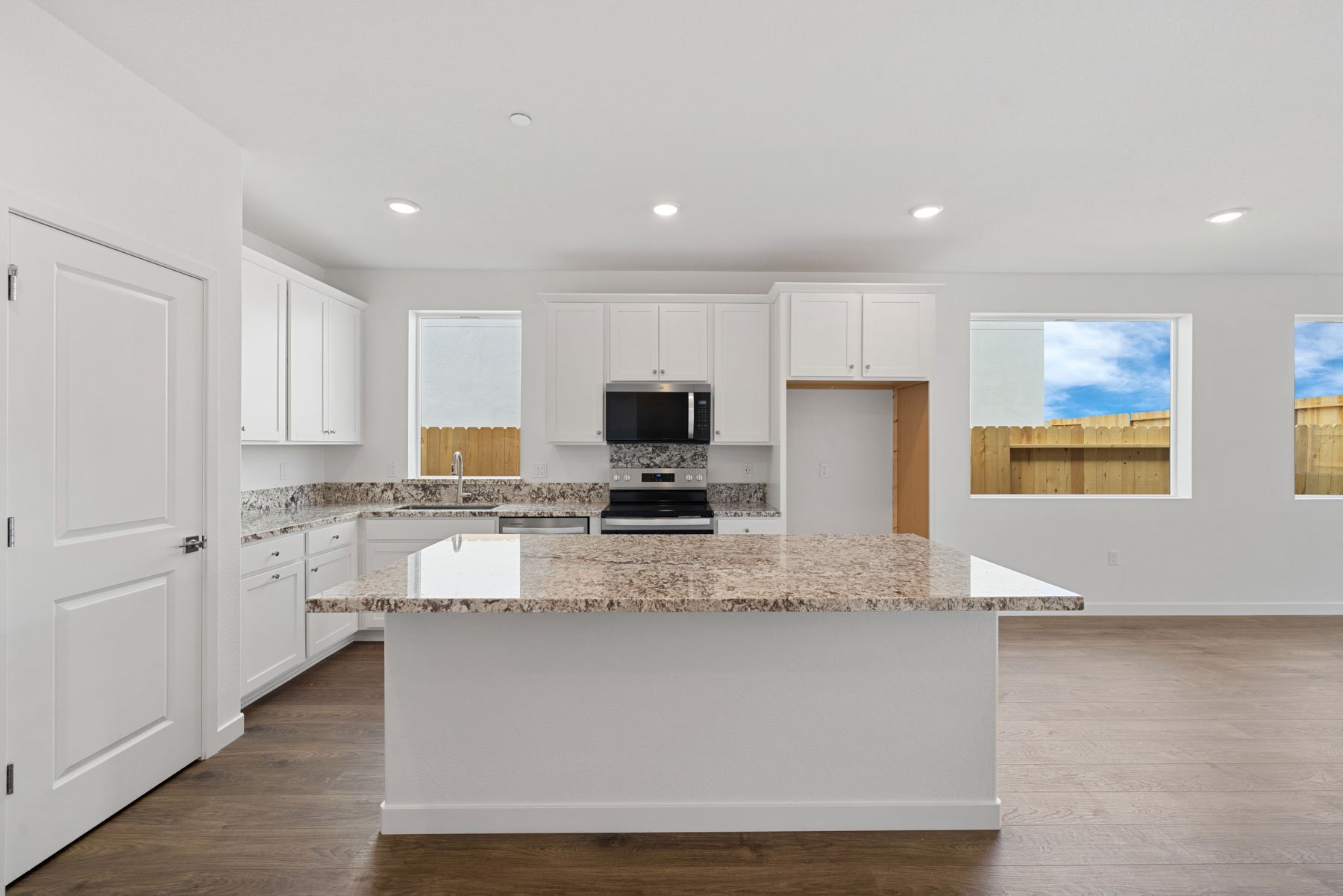 kitchen with white cabinets, island, wood floors, and multiple windows