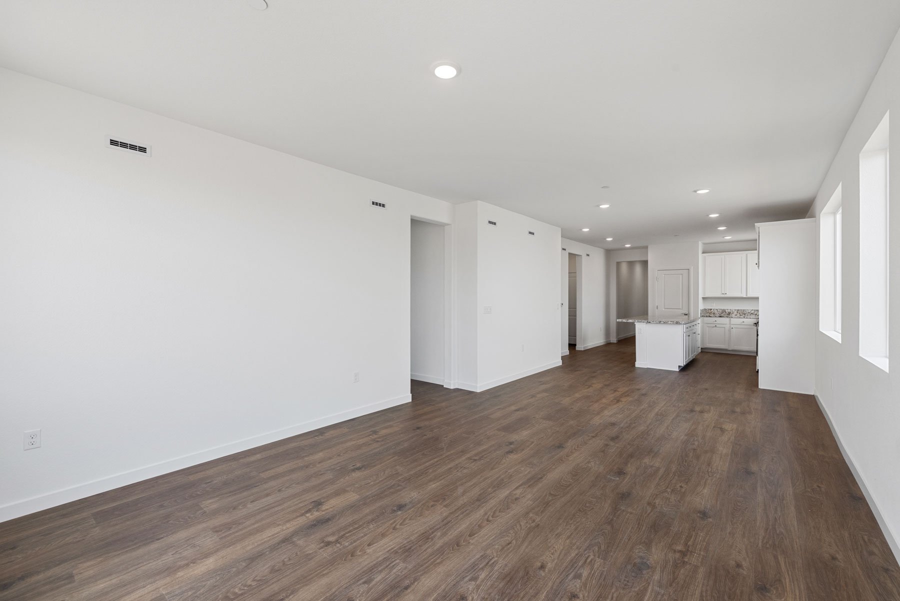great room with wood floors, white walls, recessed ceiling lights, and view of kitchen