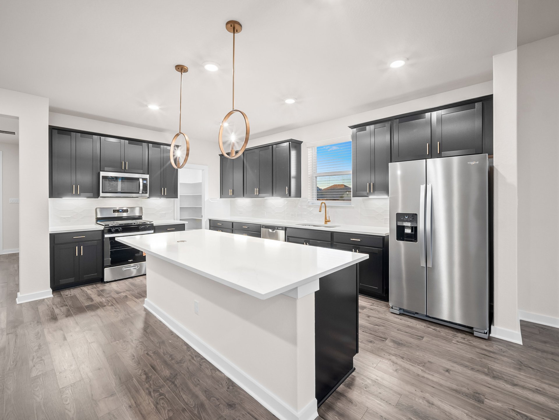 kitchen with black cabinets, quartz countertops & pendant lighting