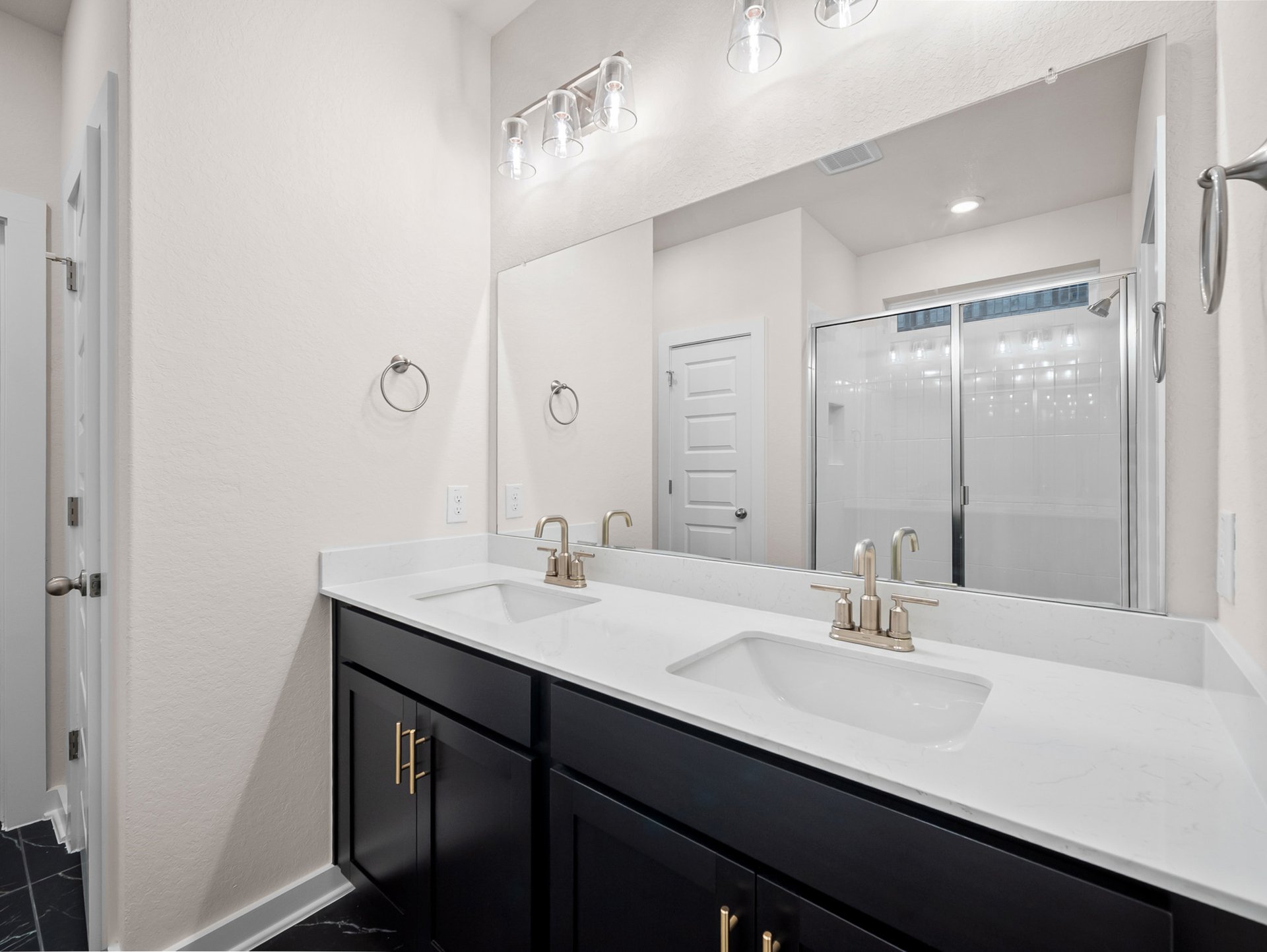 bathroom with dual sinks, quartz countertops & a walk-in shower