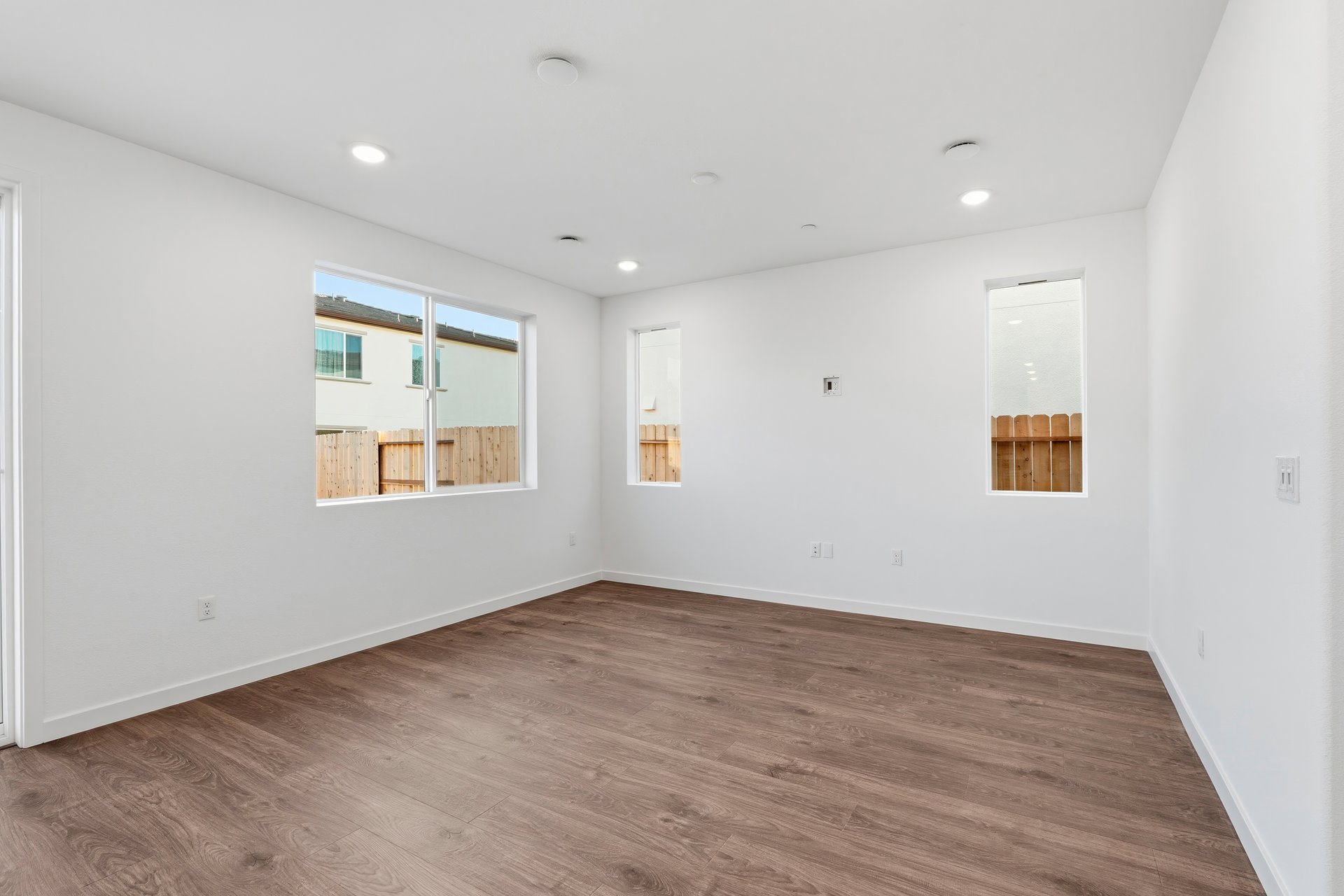 great room with wood floors, white walls, three windows, and recessed ceiling lights