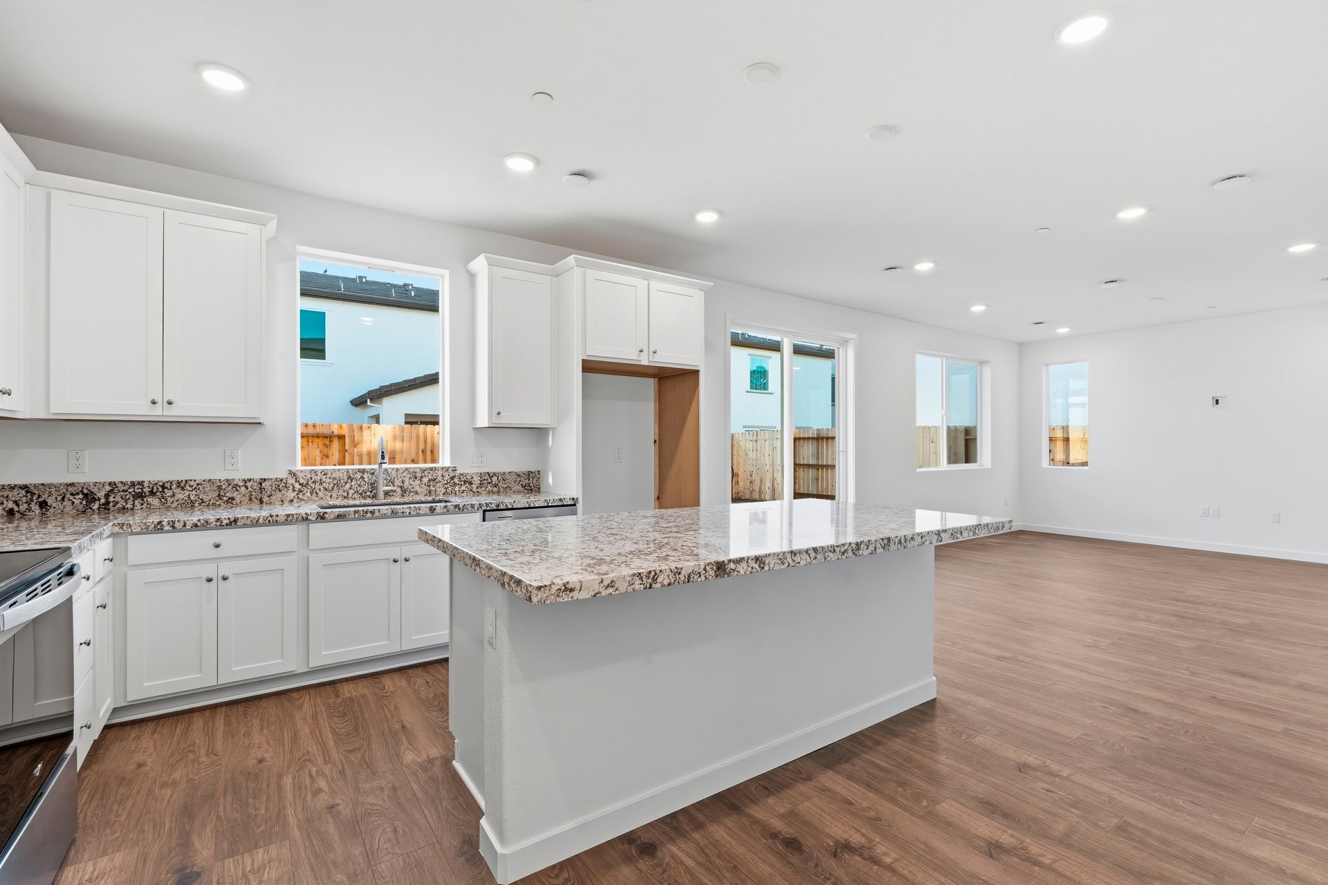kitchen with white cabinets, island, wood floors, and window above sink