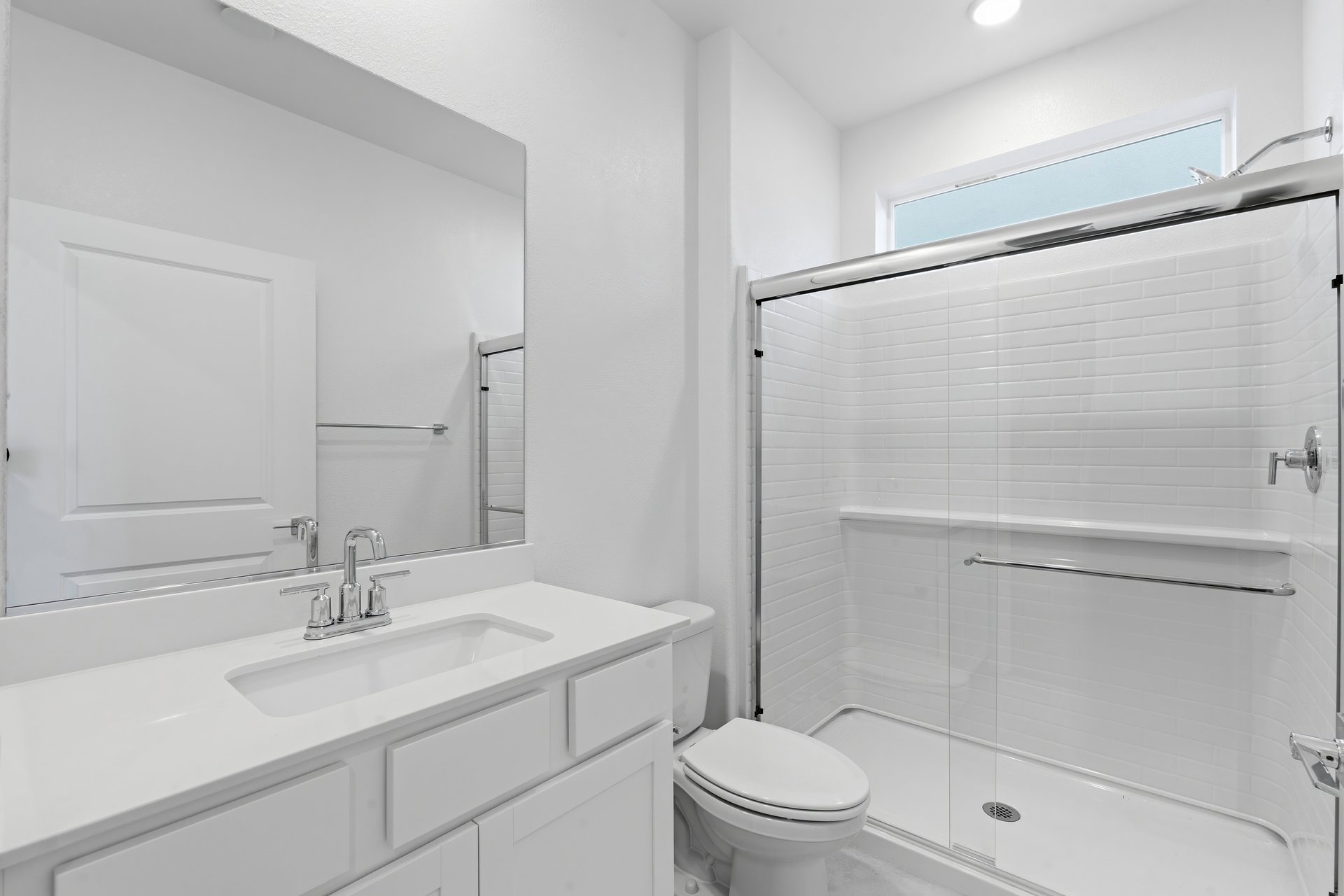 bathroom with white cabinets & counters, and window above walk-in shower