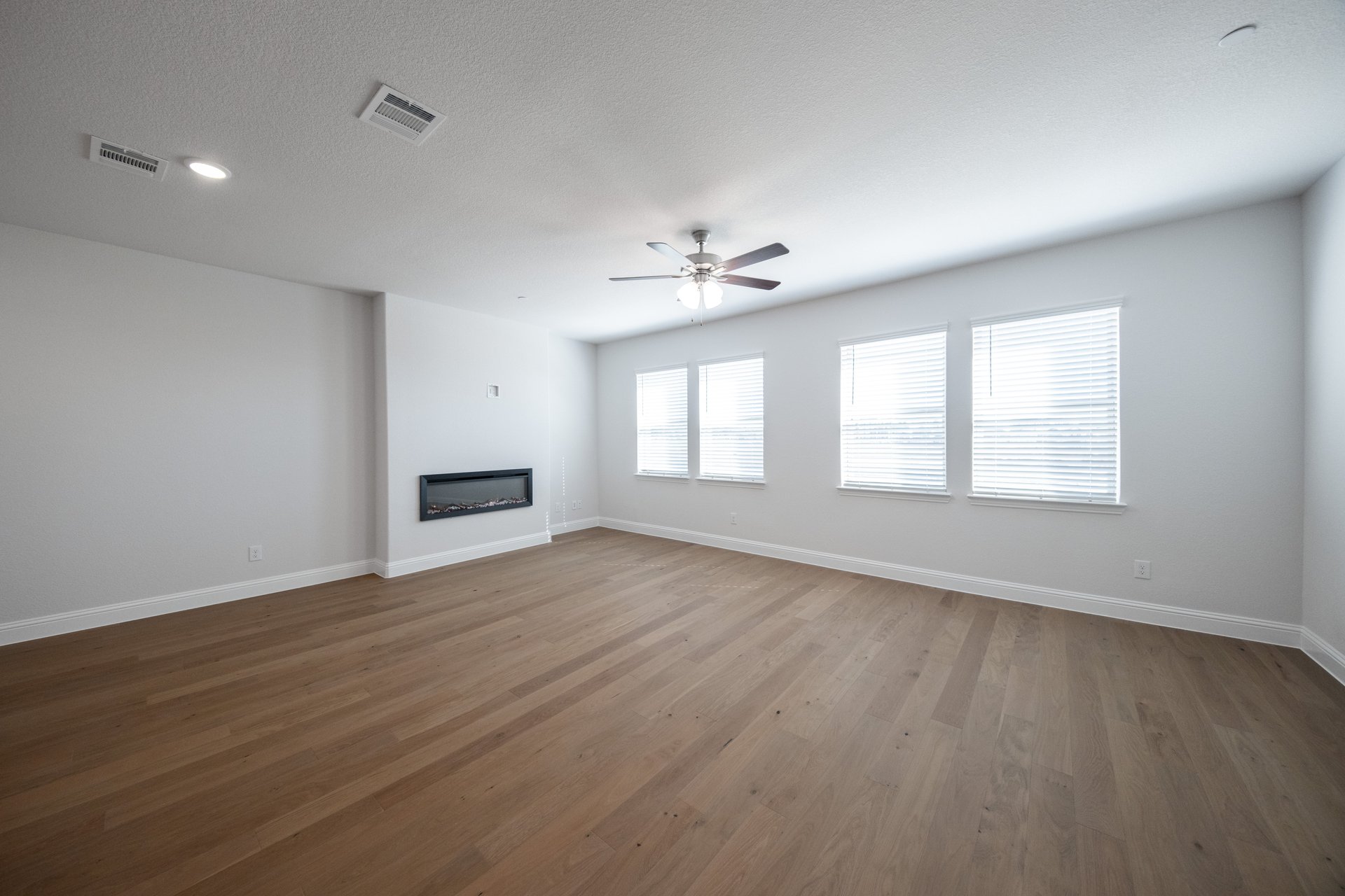 great room with windows with blinds and a fireplace 