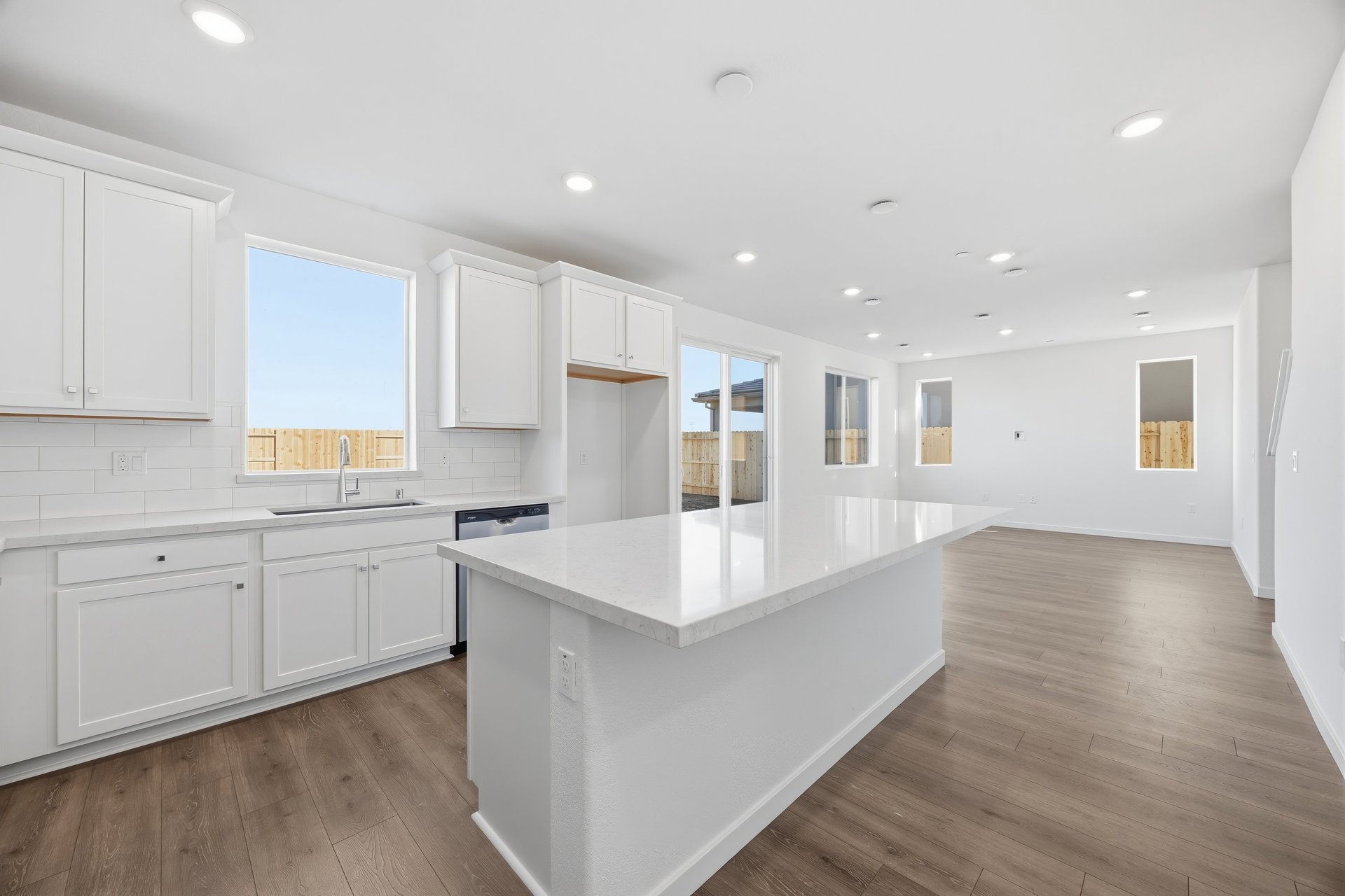 kitchen with white cabinets, white counters, wood floors, island, and window above sink
