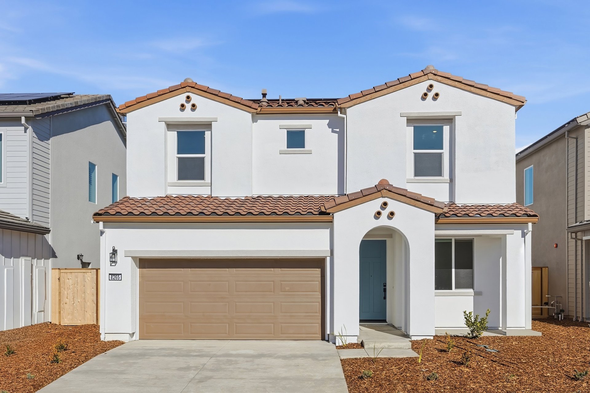 front exterior of white and brown two-story spanish style home with blue front door