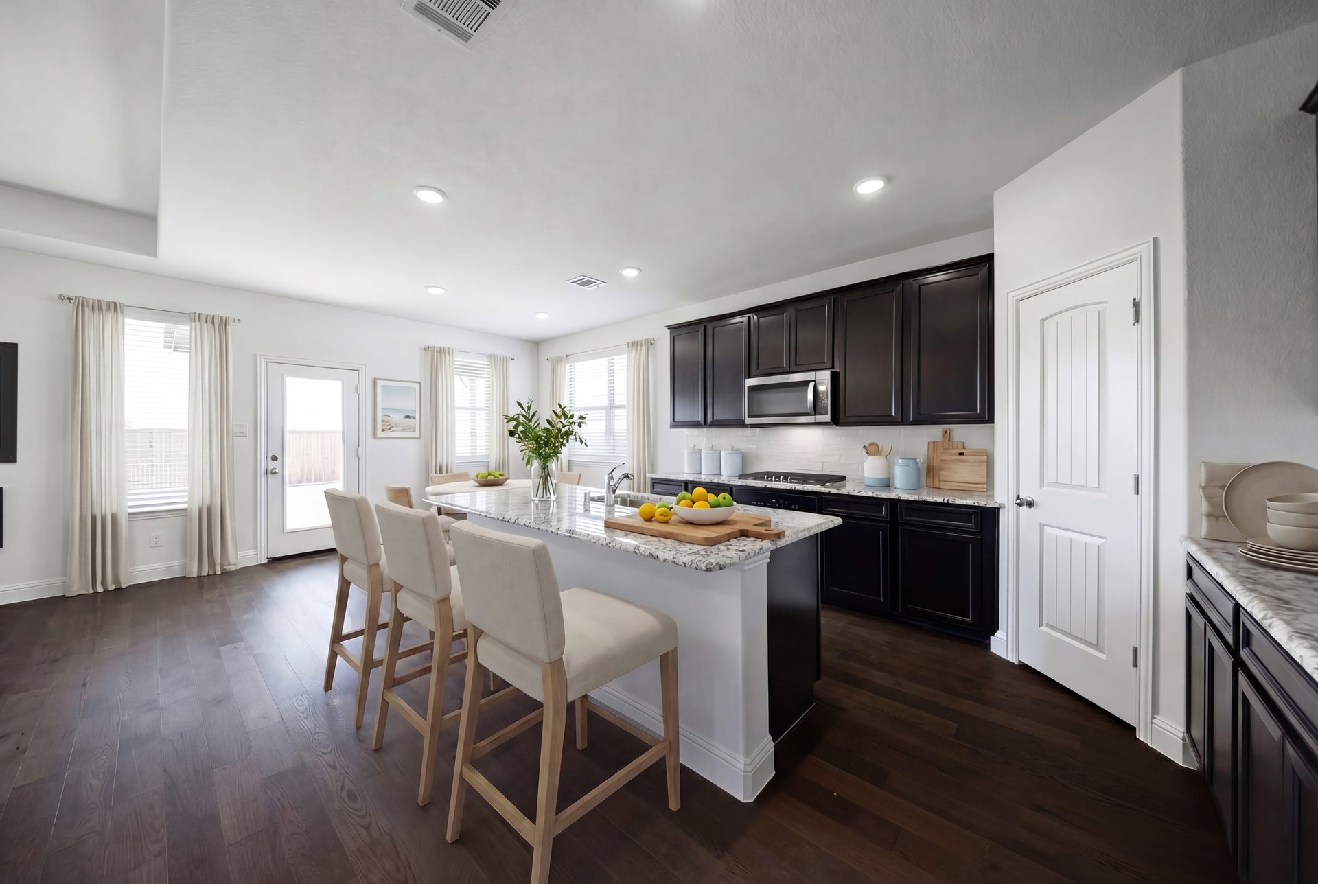 open kitchen with black cabinets and hardwood flooring
