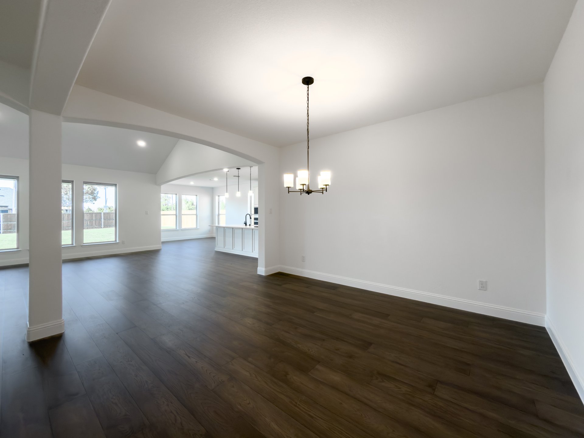 open dining room with wood floors and arch opening