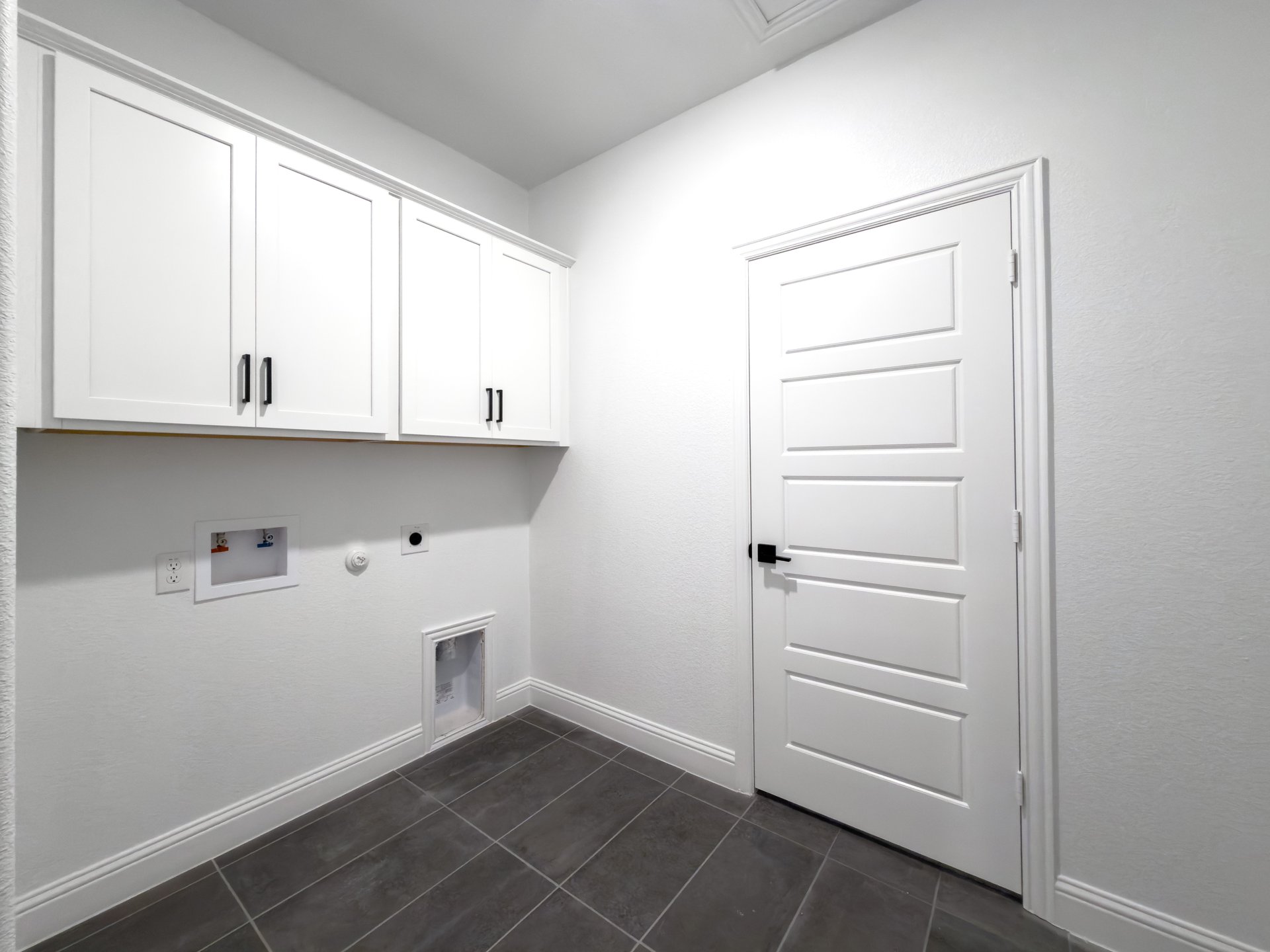 laundry room with tile floors and white upper cabinets