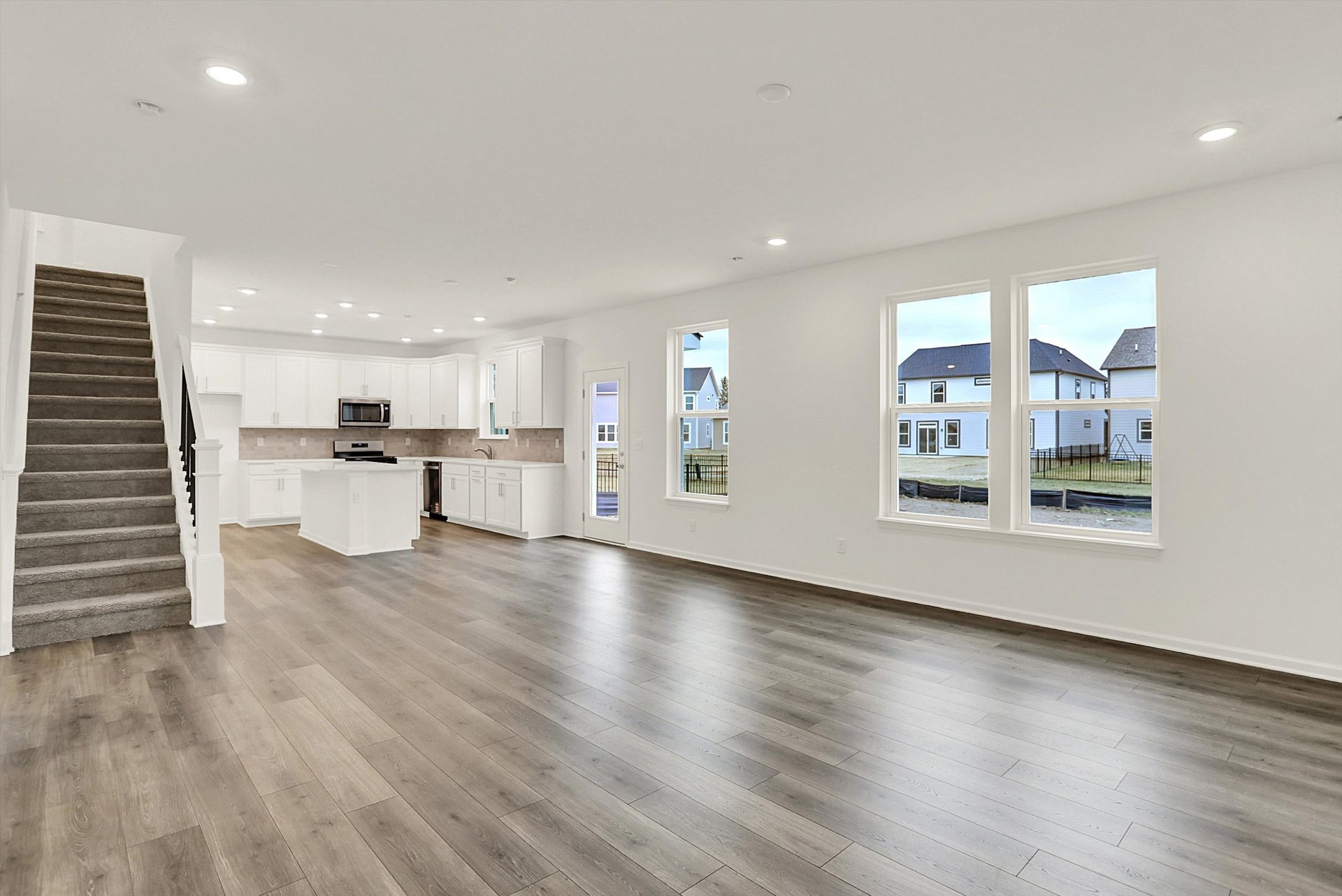 great room and open-concept dining area with wood plank flooring and white walls