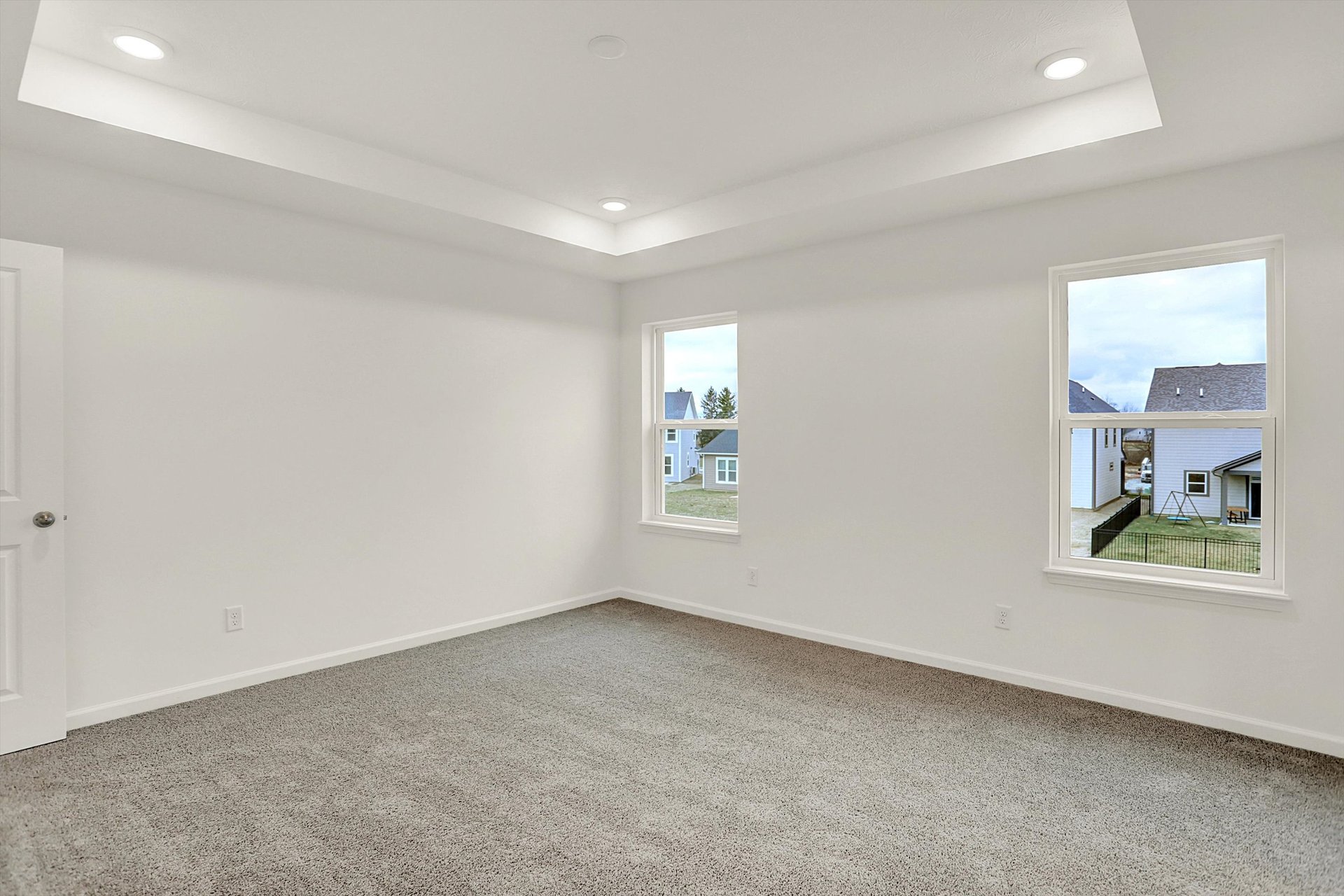 bedroom with tray ceiling and tan carpet