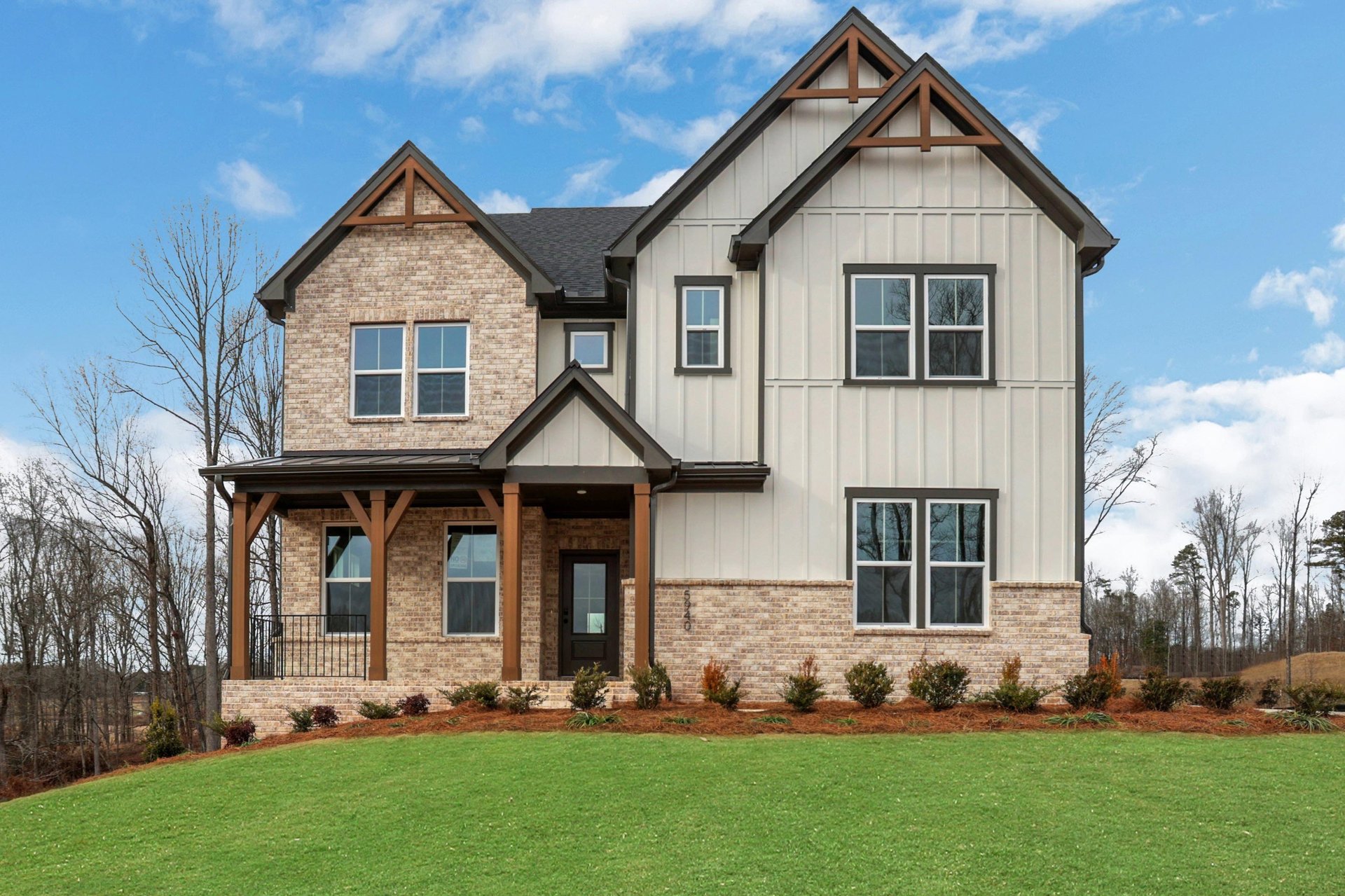front of 2-story home with brick, light siding, and dark trim