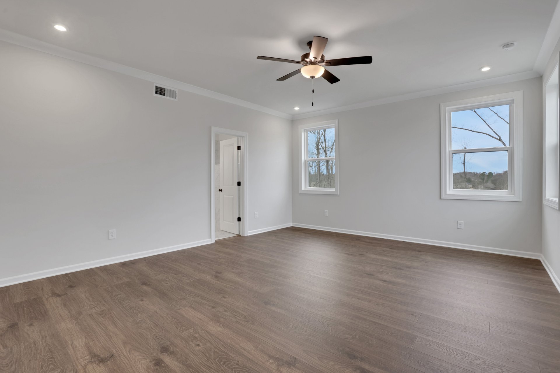 primary bedroom with windows and hard surface flooring