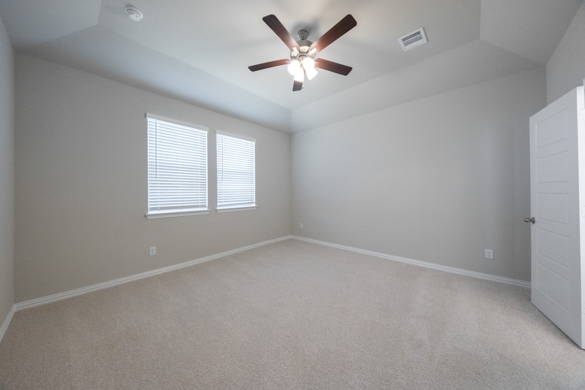 spacious primary bedroom with carpet and ceiling fan