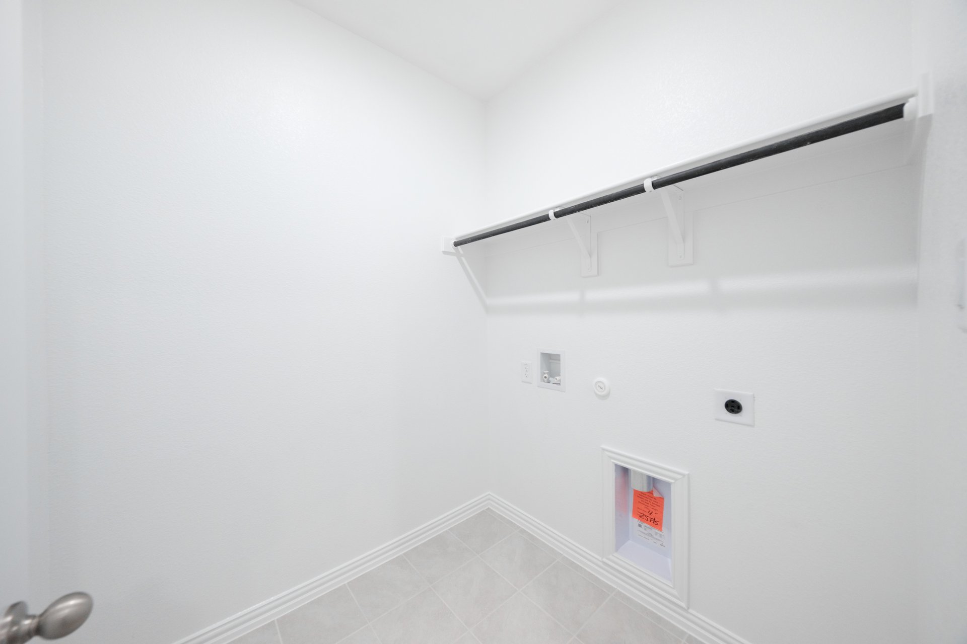 laundry room with tile floors and white shelf