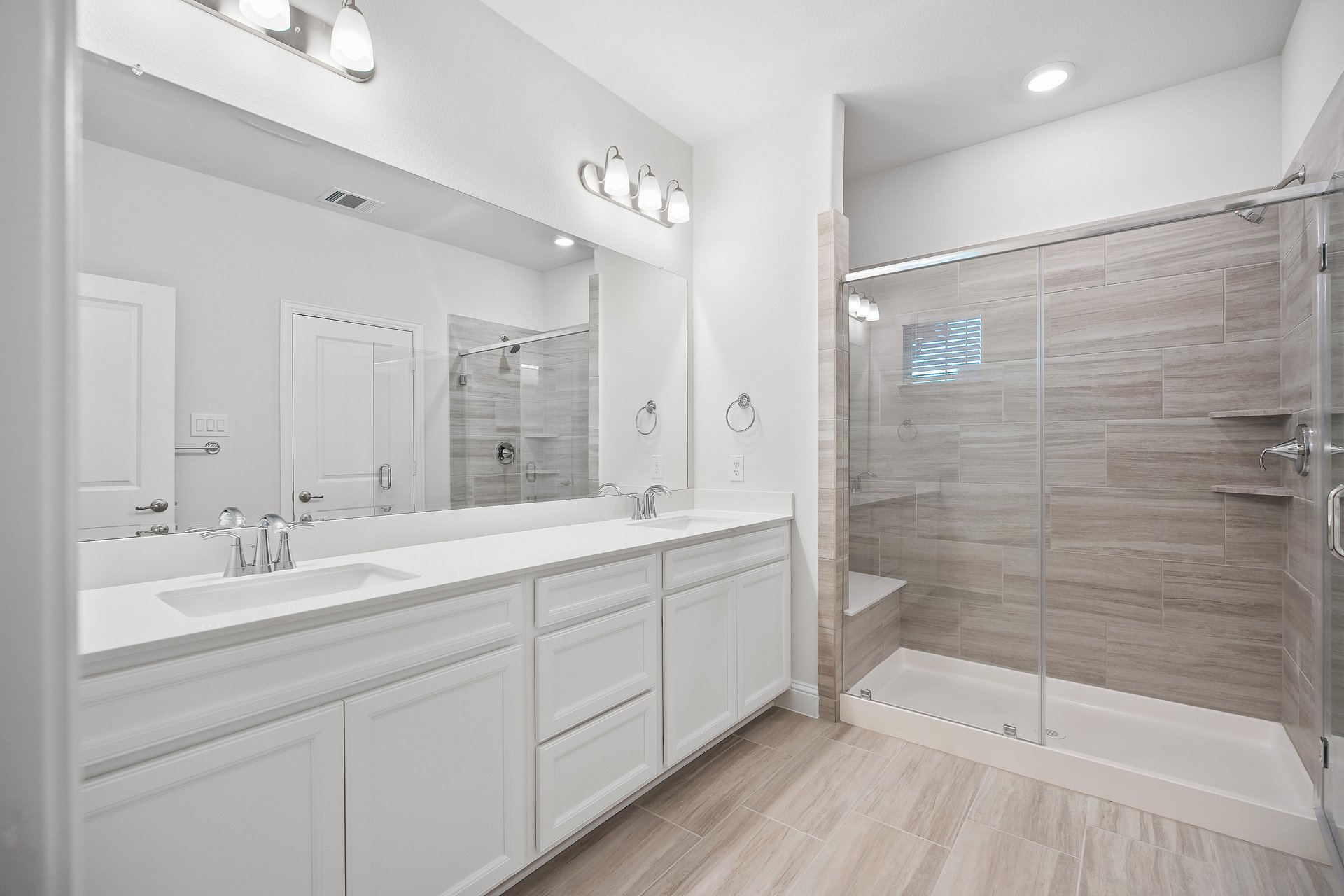 bathroom with walk-in shower and white cabinets