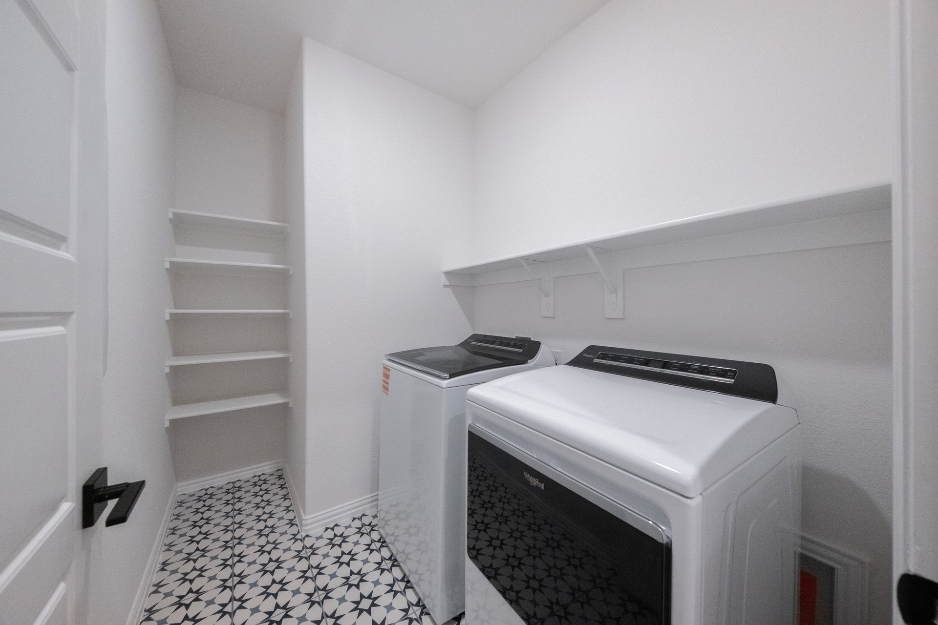 laundry room with tile floors, white shelves, washer, and dryer