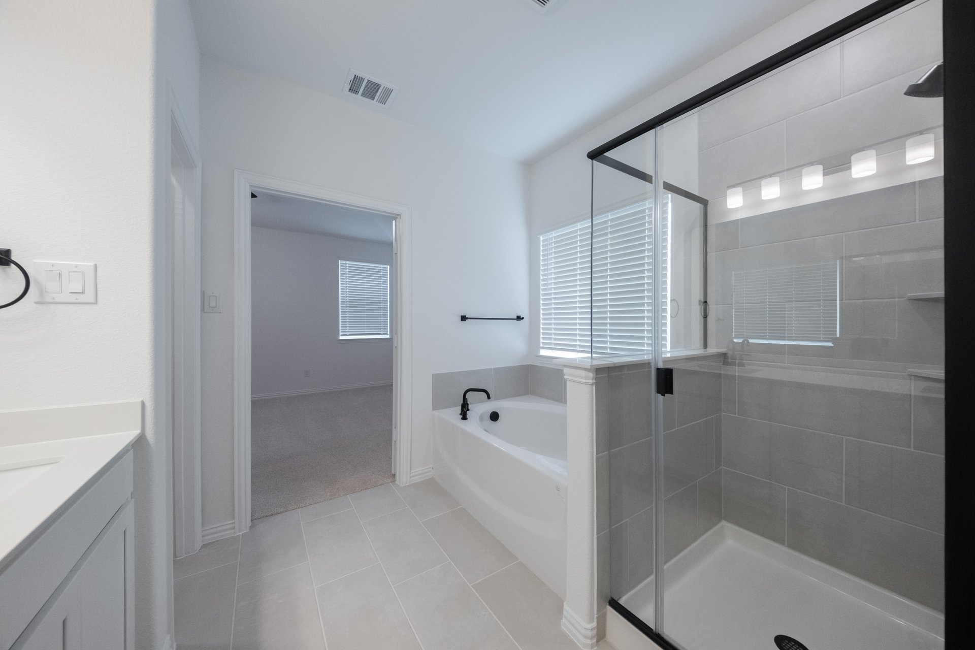 primary bathroom with tile floors and white cabinets