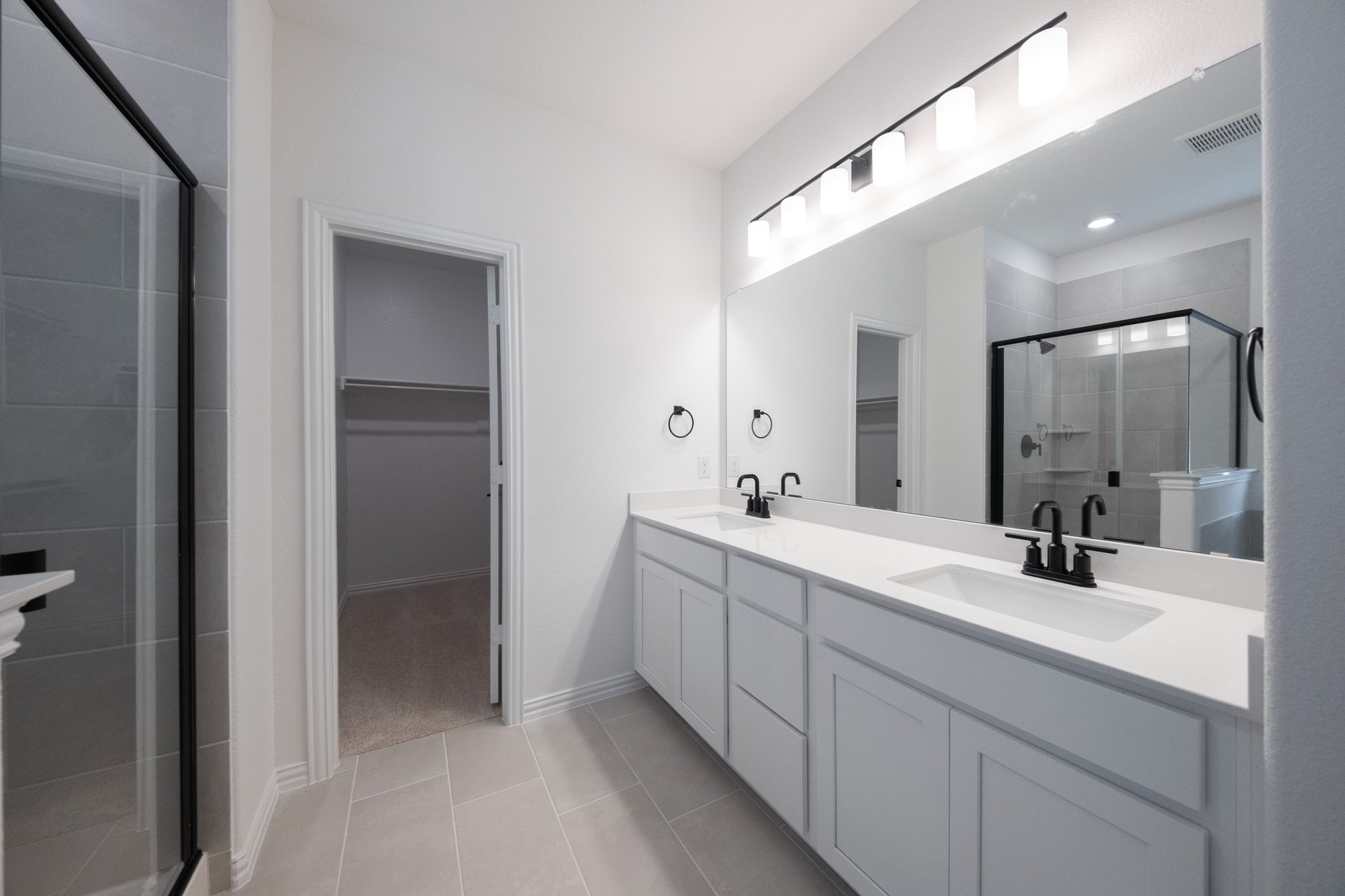 primary bathroom with tile floors and white cabinets