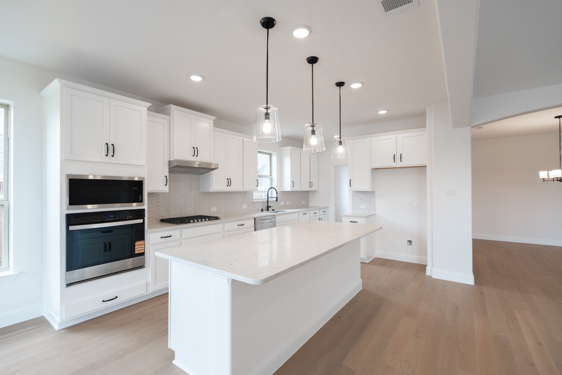 open kitchen with white cabinets and island pendants