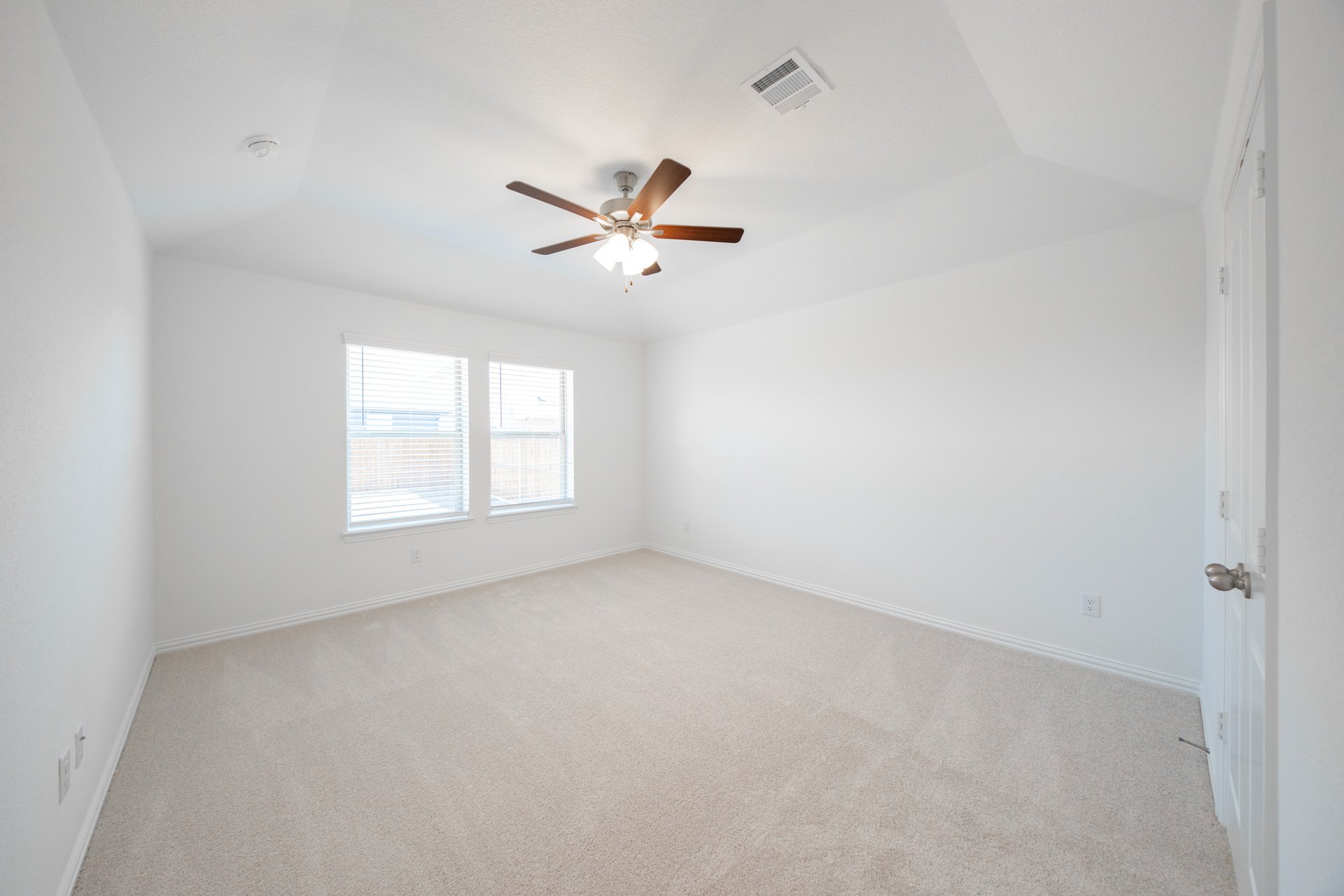spacious primary bedroom with carpet and ceiling fan