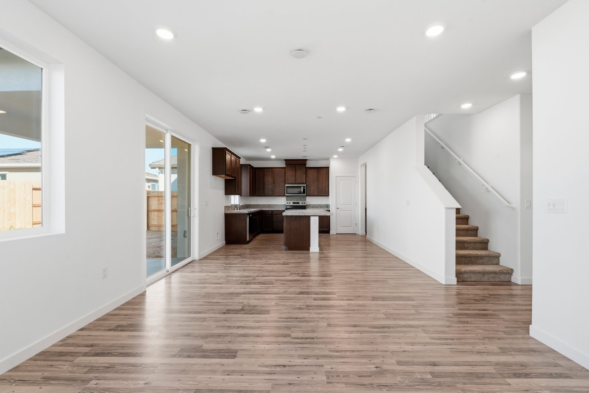 great room with wood floors, white walls, window, sliding glass door, and view of kitchen