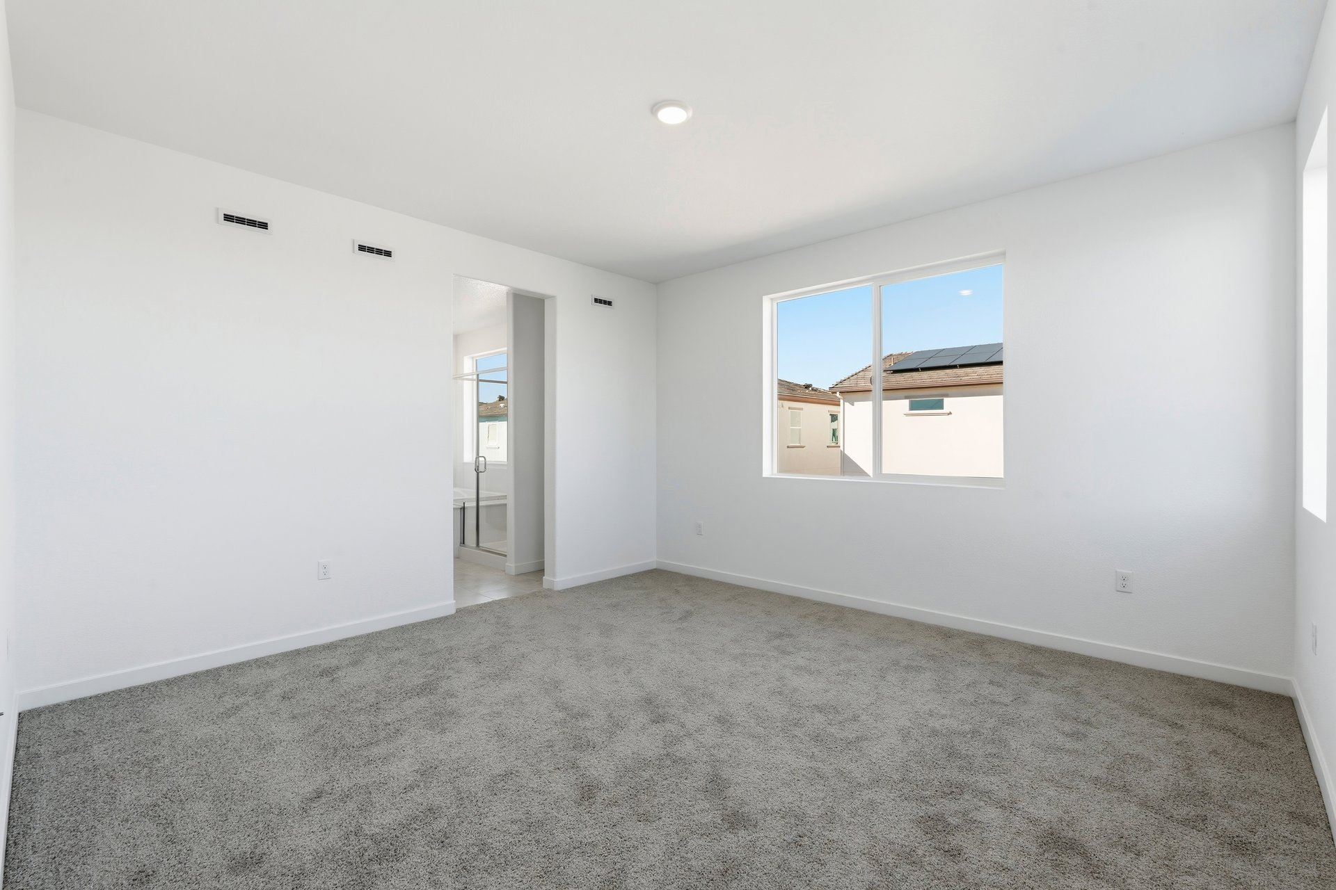 bedroom with gray carpet, white walls, window, and view of attached bathroom