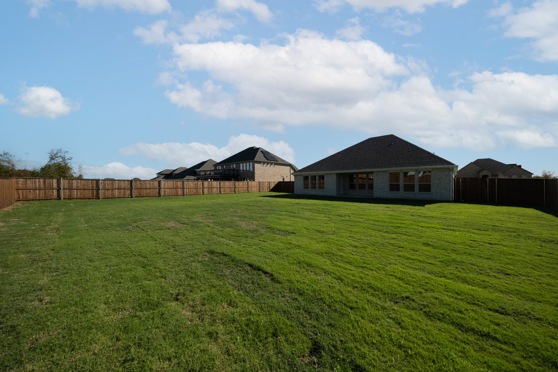 large fenced backyard with grass