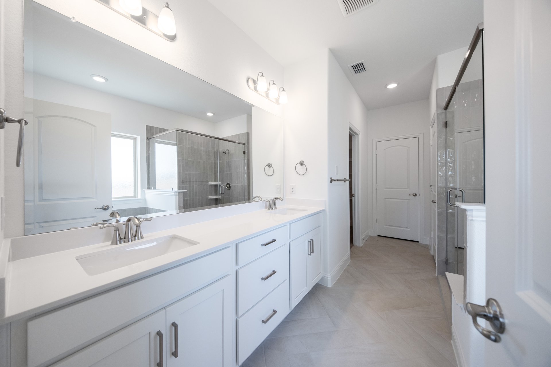 primary bathroom with large mirror and white countertops 