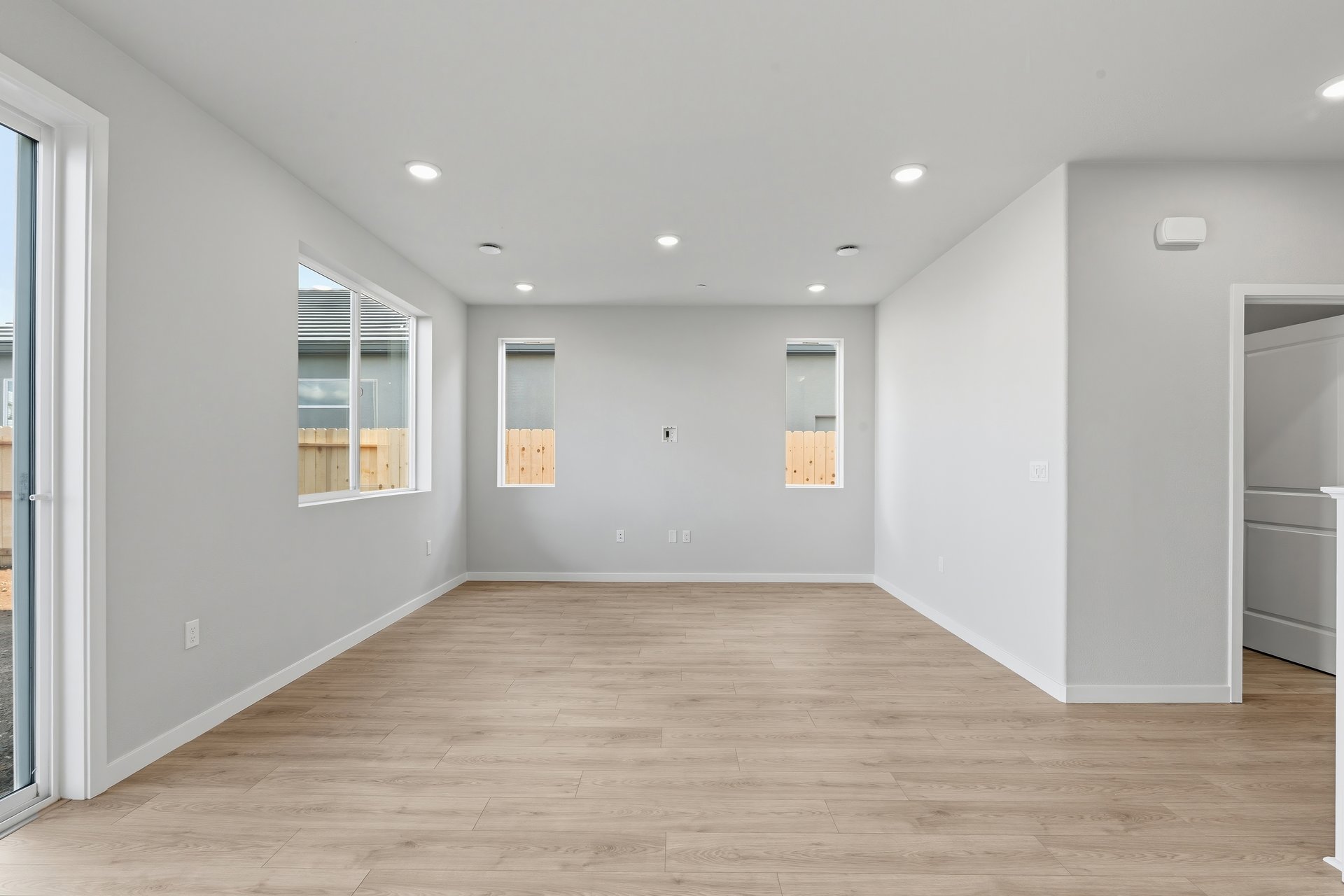 great room with light gray walls, three windows, and light wood floors