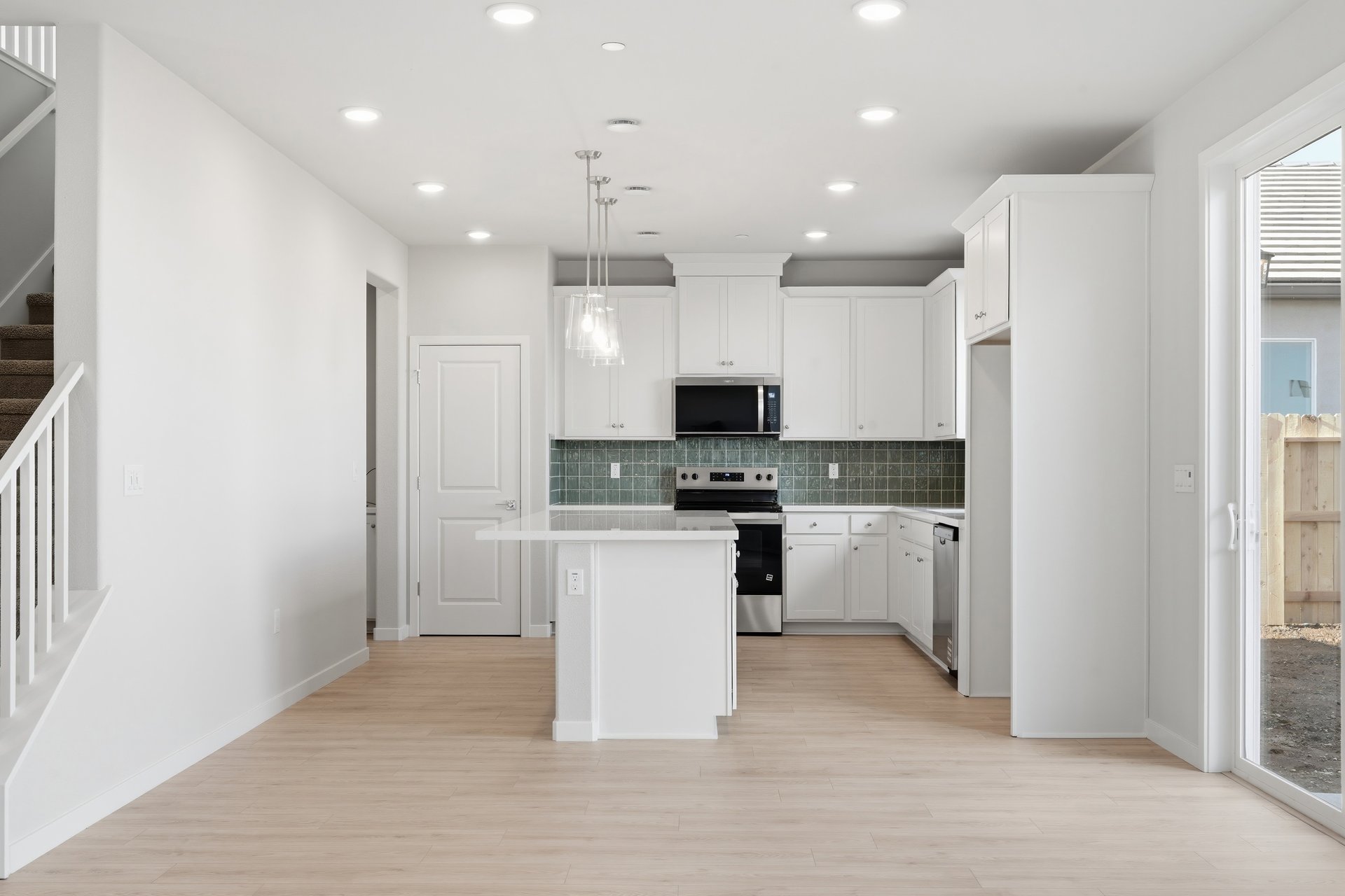 kitchen with white cabinets, white counters, green tile backsplash, and light wood floors