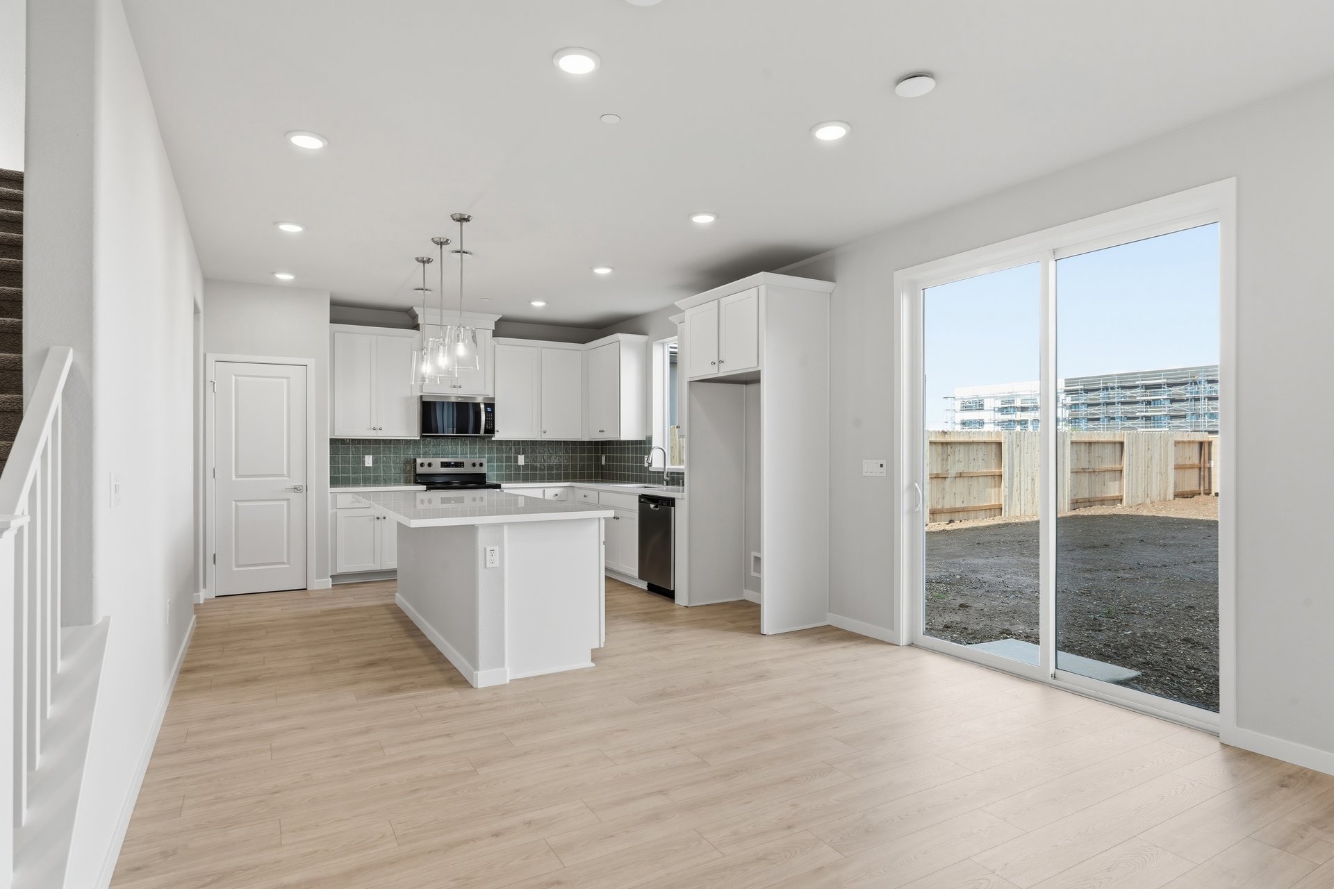 dining room with light wood floors, white walls, sliding glass door to backyard, and view of kitchen with white cabinets