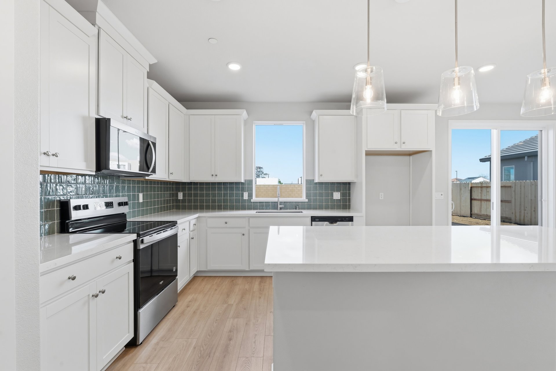 kitchen with white cabinets, white quartz counters, green tile backsplash, and window above sink