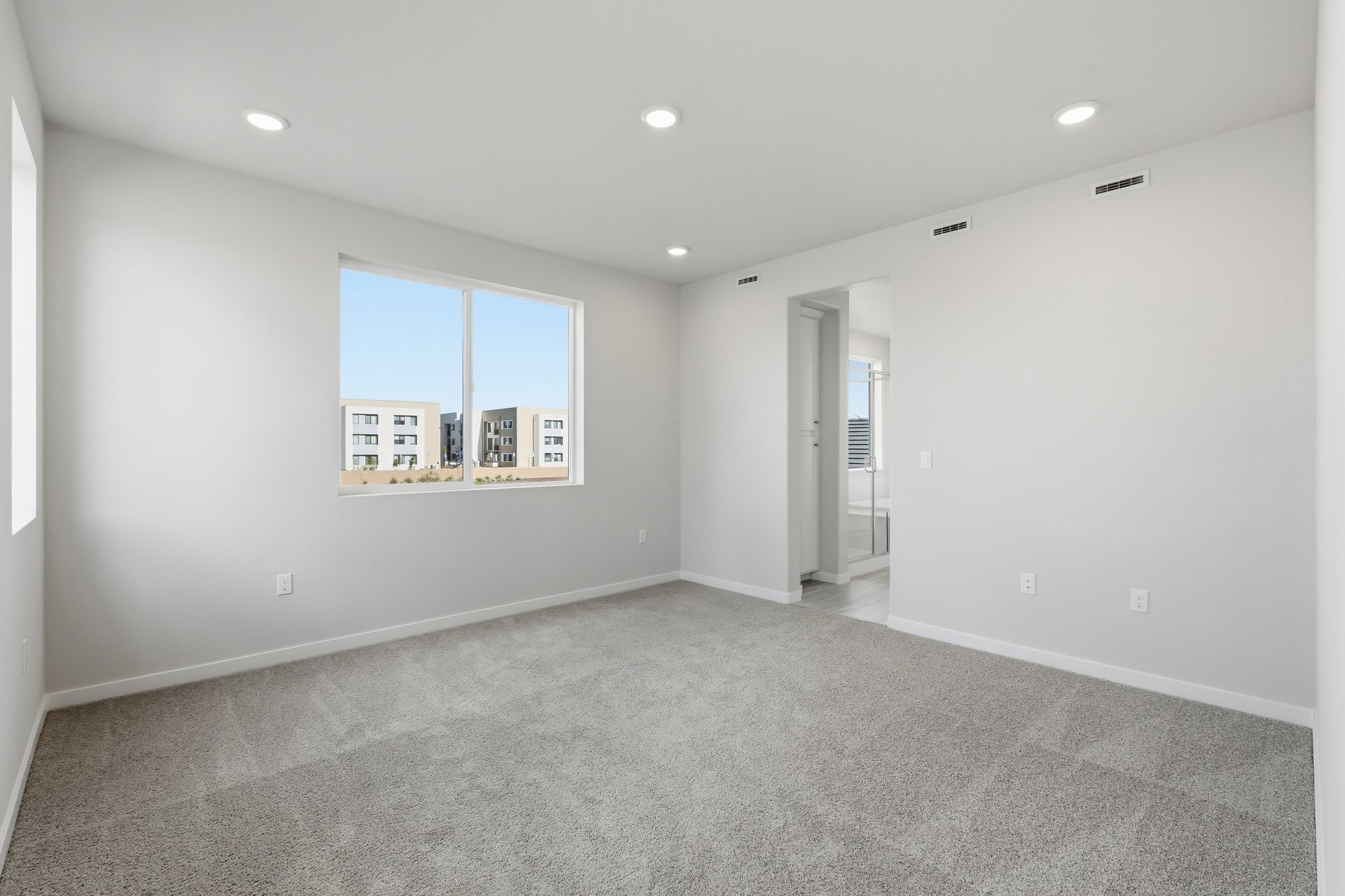 bedroom with gray carpet, window, and view of attached bathroom